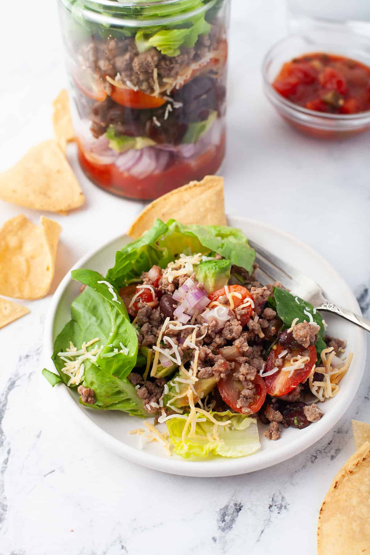 Taco salad in a jar with plated salad in front.
