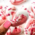 Holding single meringue cookie over plate.