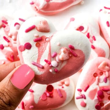 Holding single meringue cookie over plate.