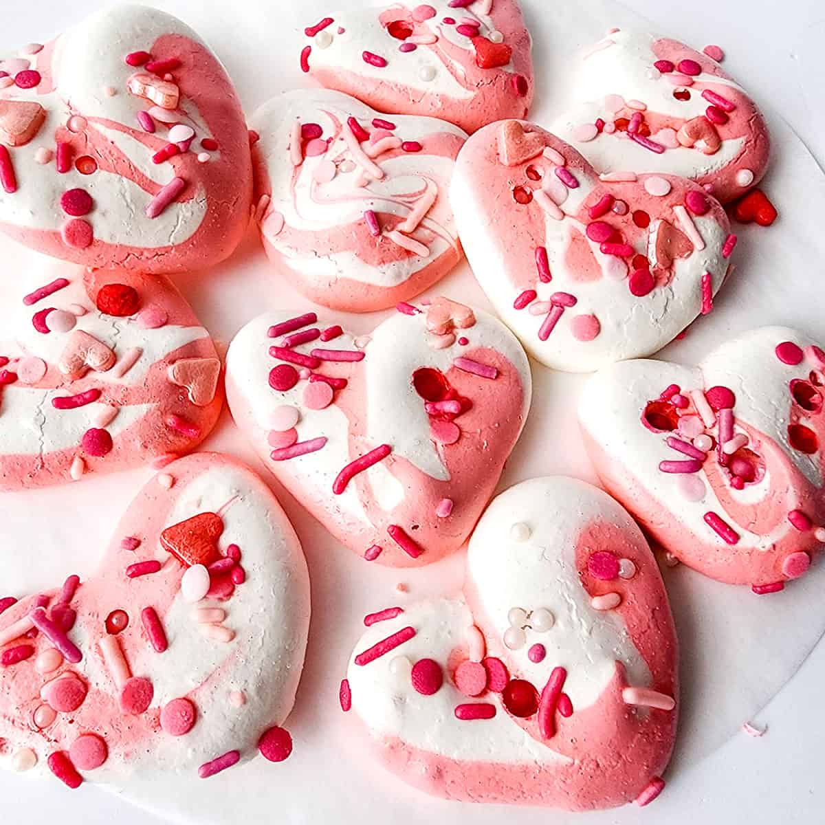 Valentines soft meringue cookies in shades of pink on table.