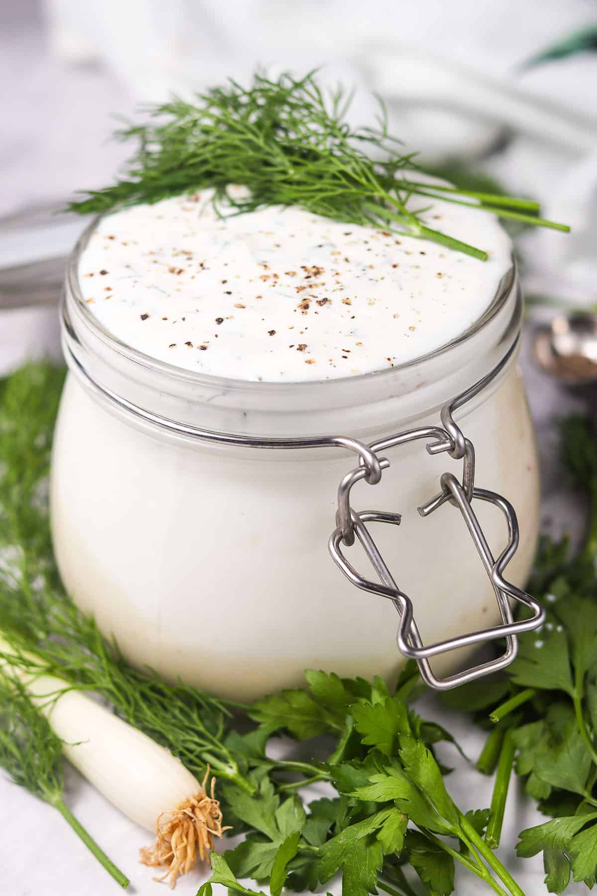 Creamy Herb Ranch Dressing in jar with dill garnish.