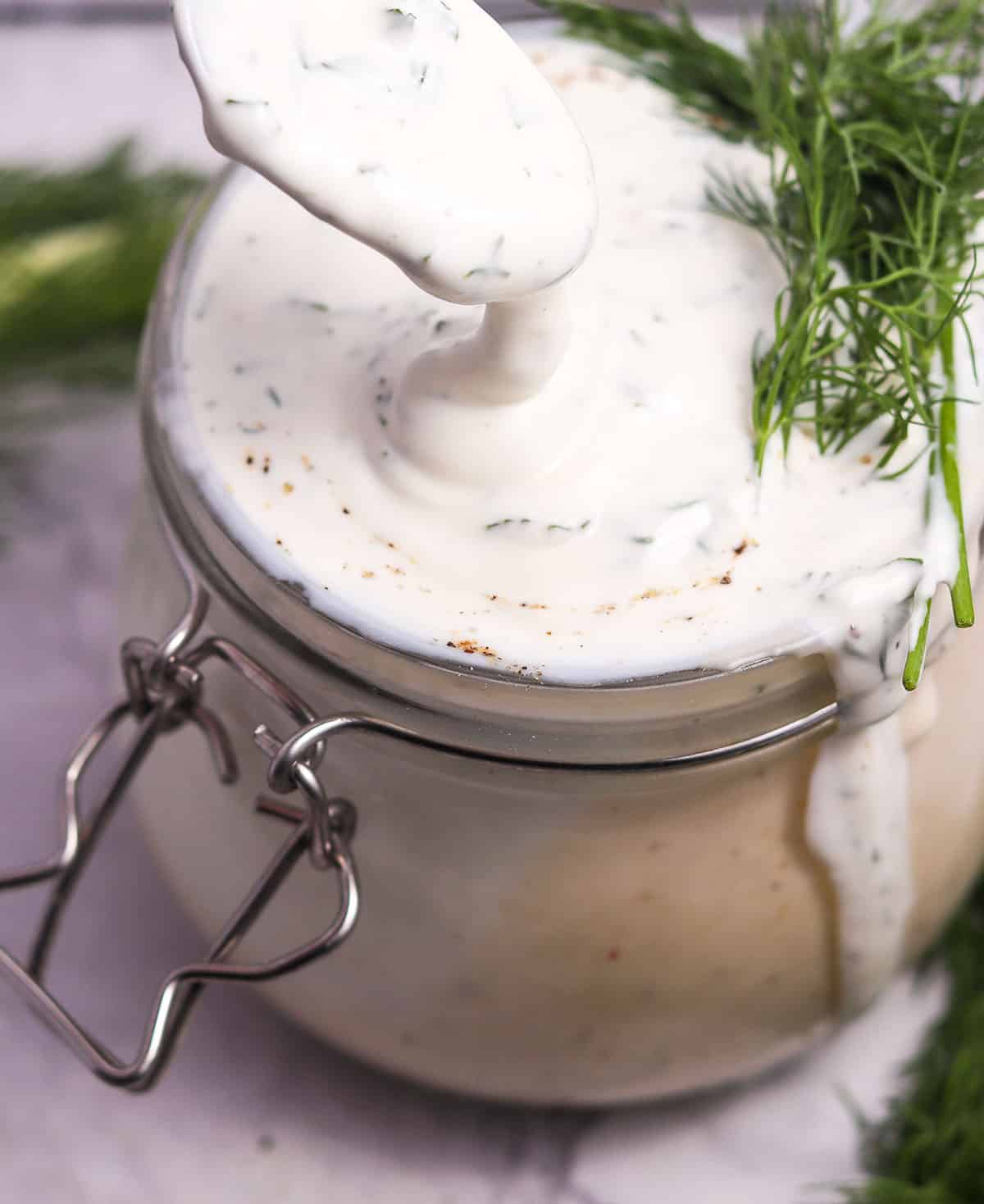 Spoonful of dressing dripping into jar.