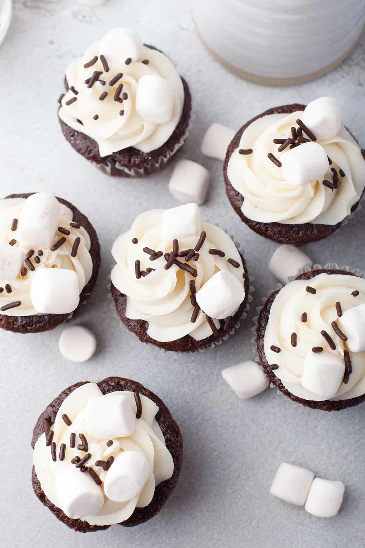 Overhead of frosted hot chocolate cupcakes on table.