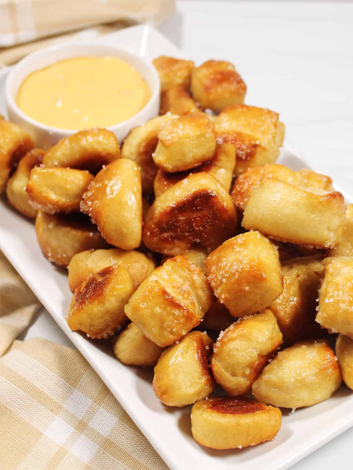 Pretzel bites with pizza dough on platter with cheese dip.