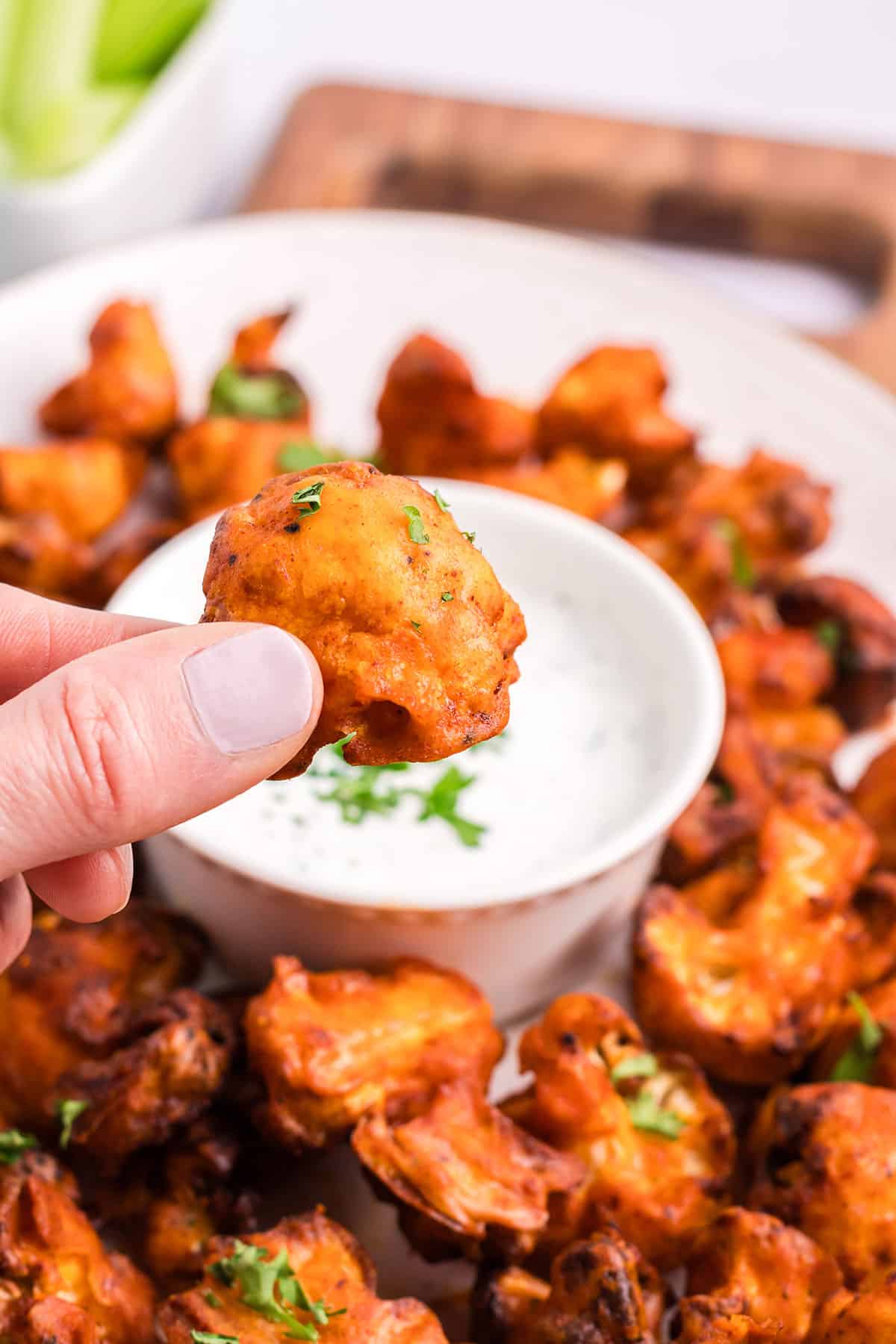 Holding an air fried cauliflower wings over platter.