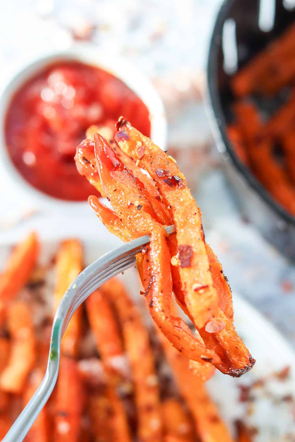 Spicy sweet potato fries on fork.