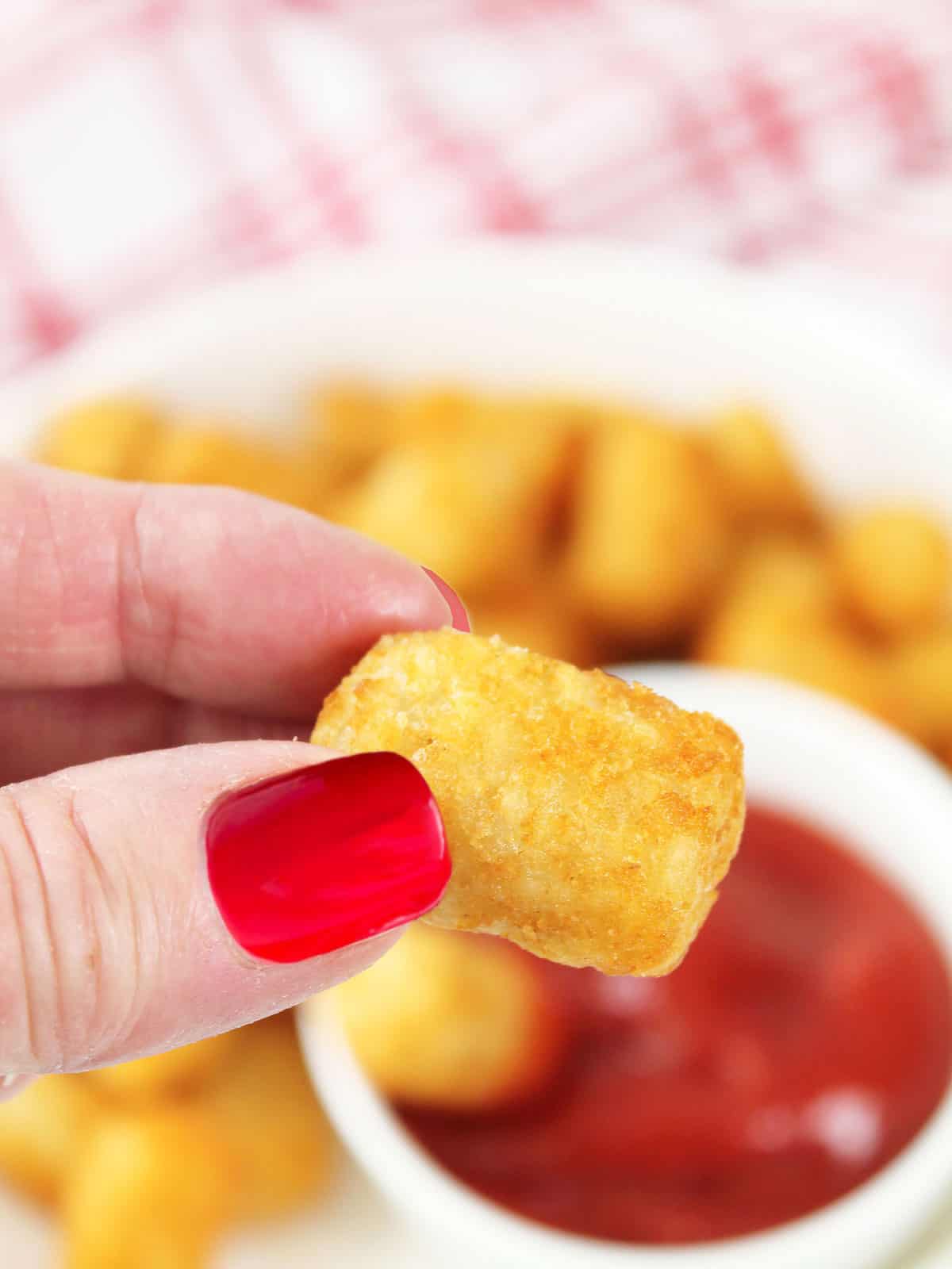 Holding tater tot over serving bowl.