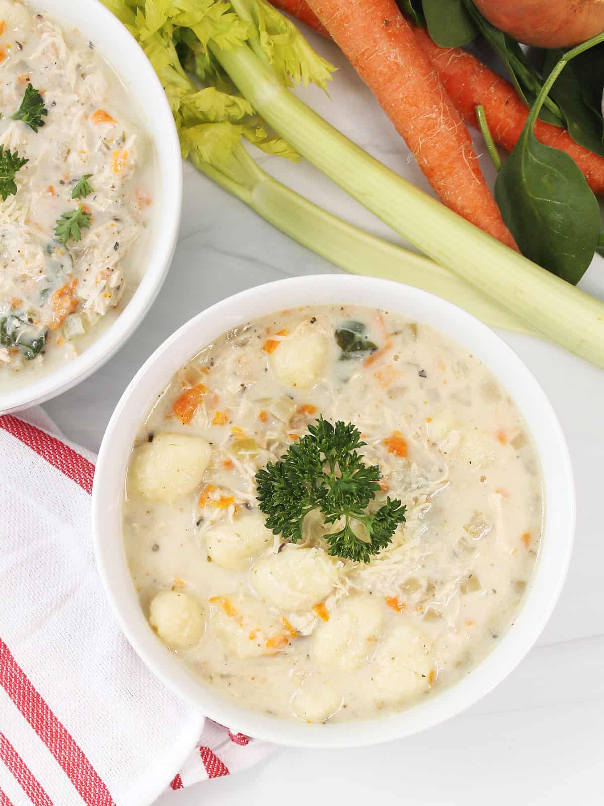 Overhead of creamy chicken gnocchi soup with garnish.