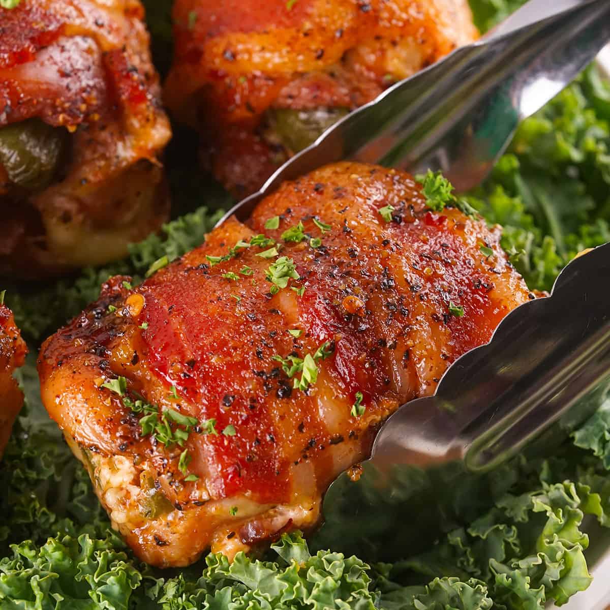 Lifting smoked chicken thigh from platter.