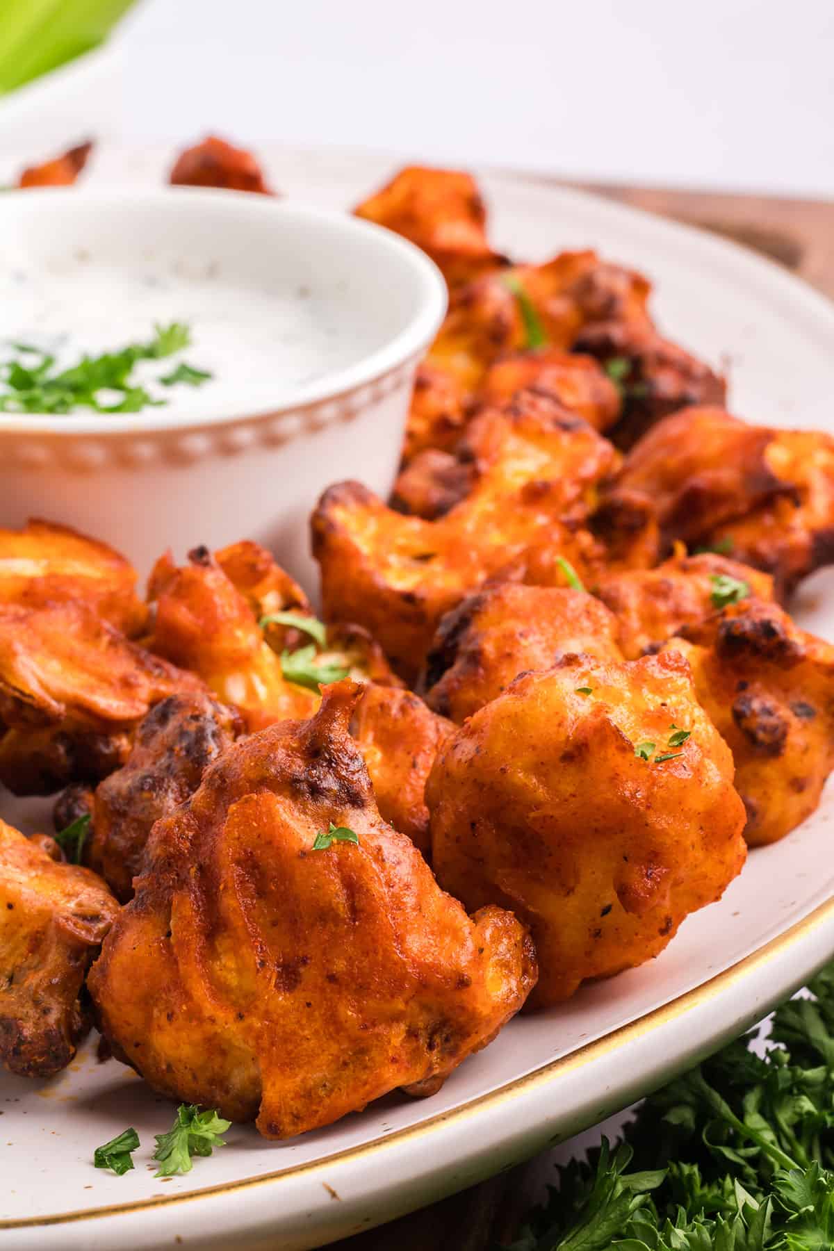 Partial view of crispy spicy air fryer cauliflower wings on platter.