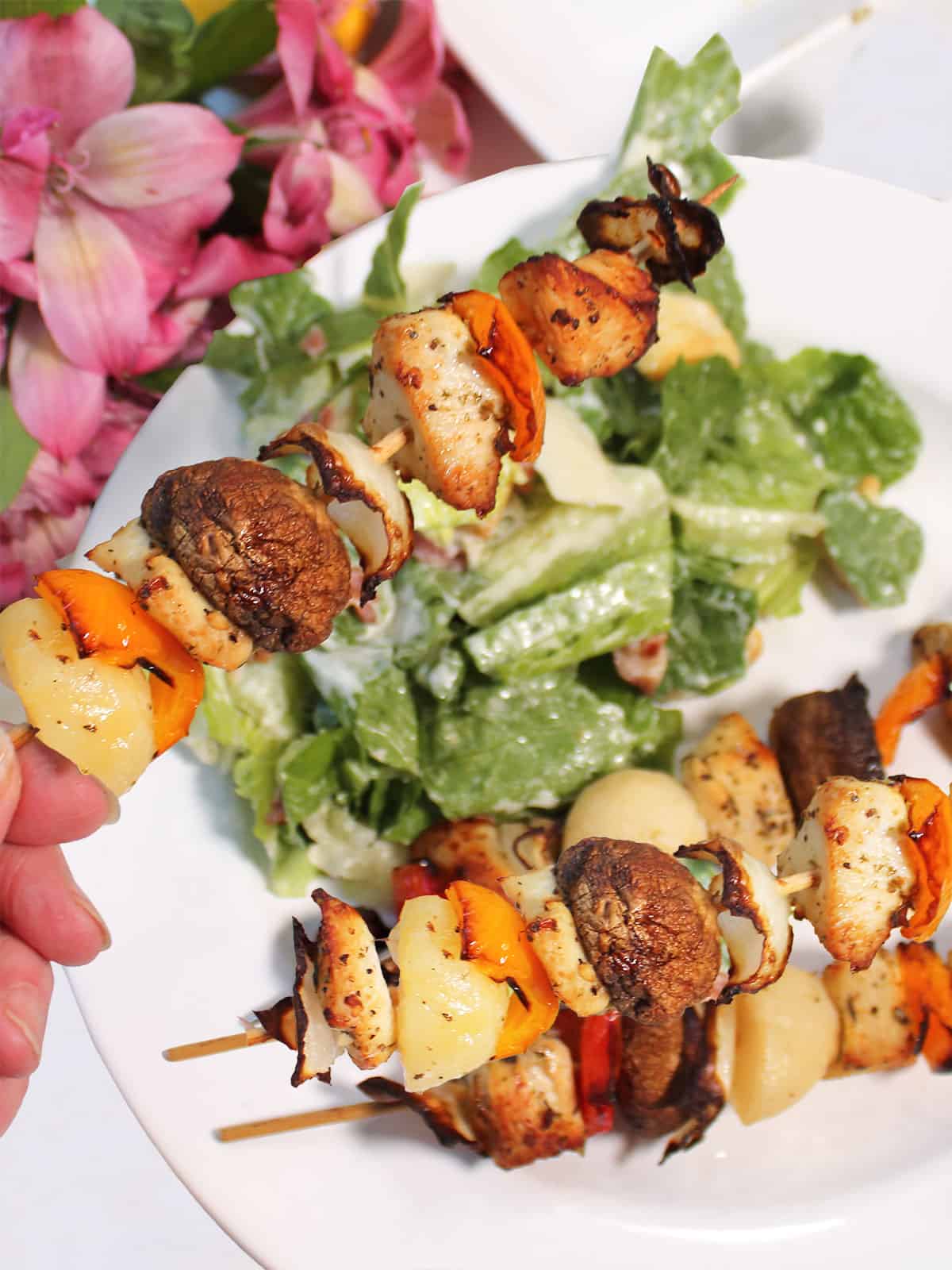 Holding air fryer chicken skewer over dinner plate.