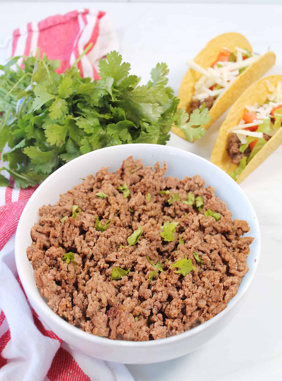 Air fryer ground beef in bowl next to two tacos.