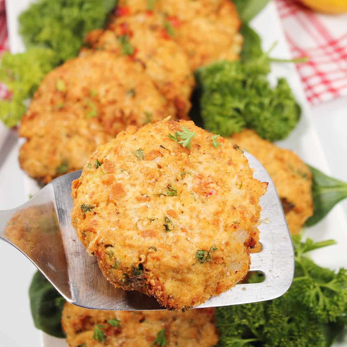Air fryer salmon patties on platter with one on spatula.