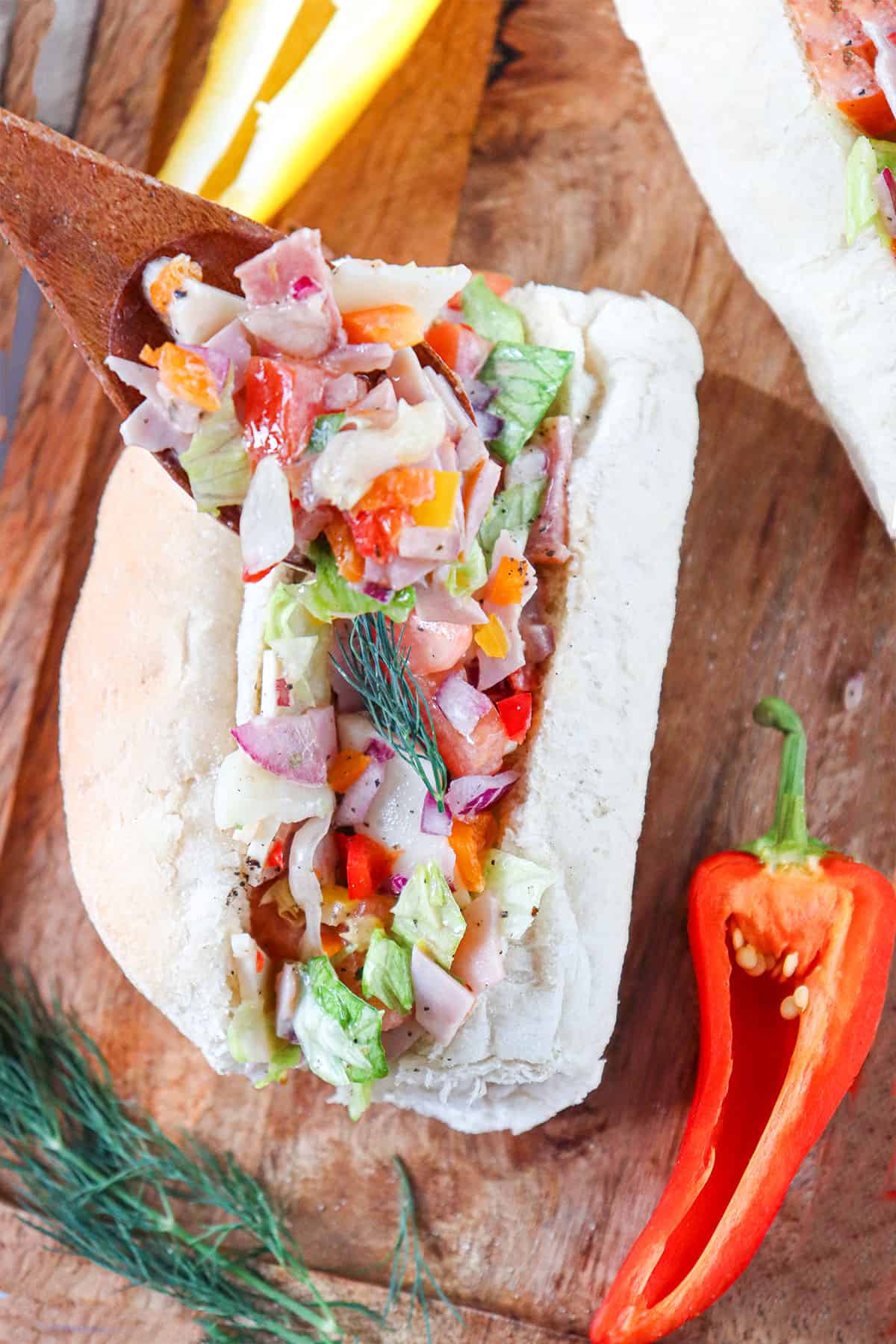 Spooning filling into hoagie roll.