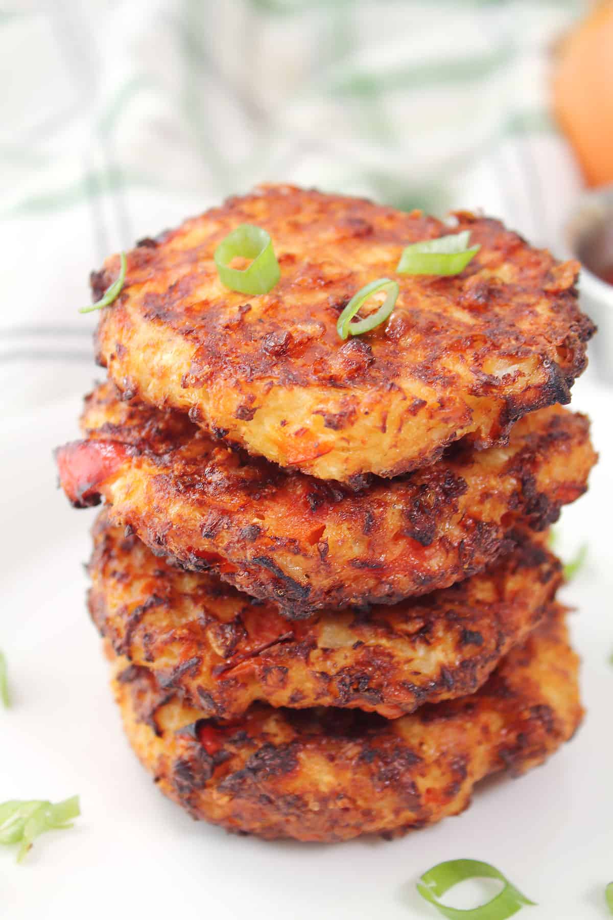 Stacked hash browns with green onion garnish.