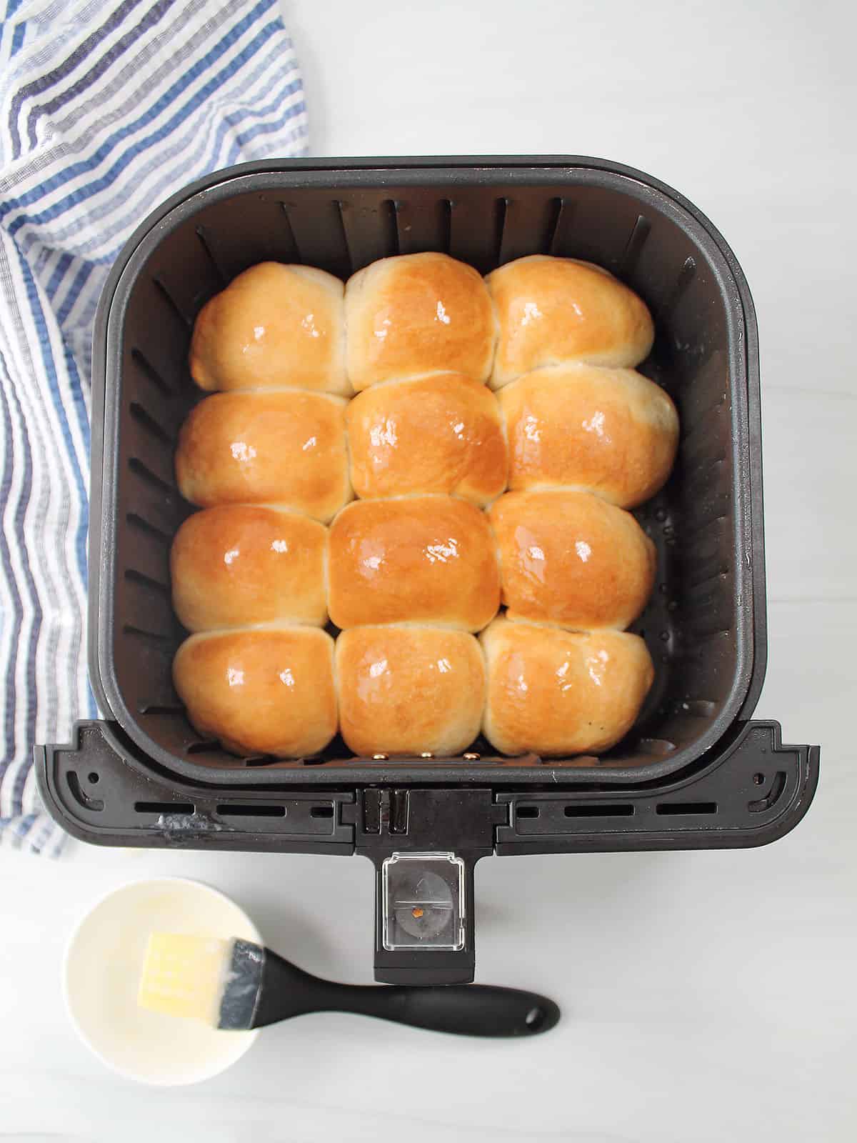 Buttered air fryer rolls in air fryer basket.