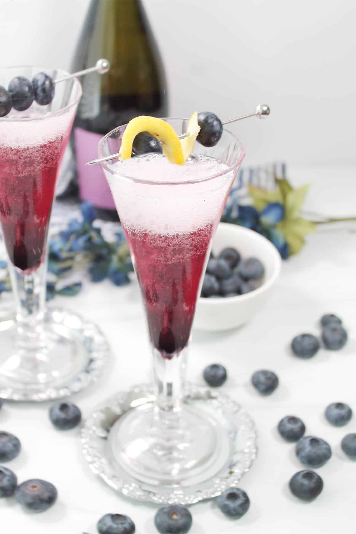 Closeup of bellini cocktail with scattered blueberries.