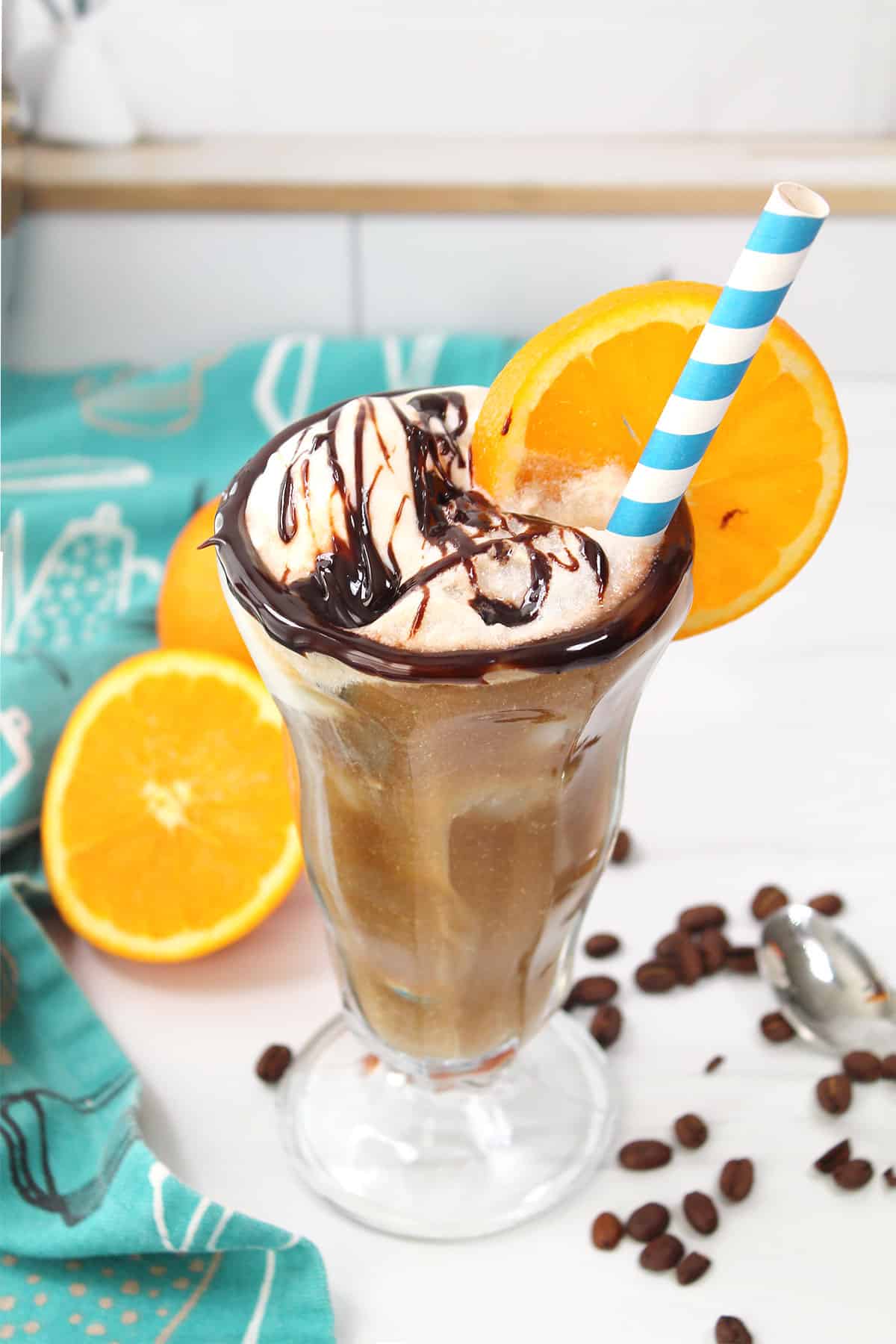 Cold brew float with chocolate drizzle, orange wheel and straw.