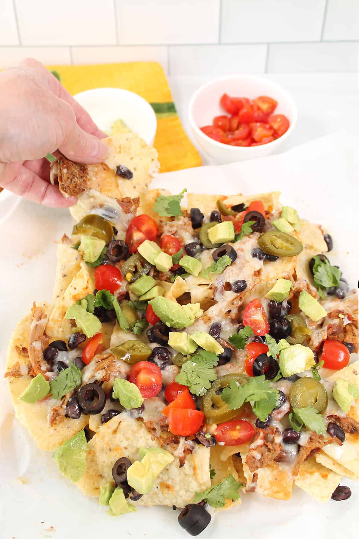 Grabbing a nacho chip from plated air fryer pulled pork nachos.