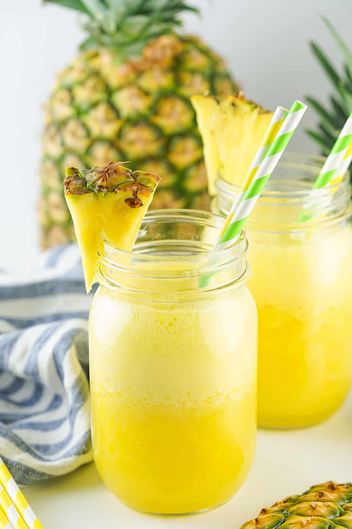 Two mason jars of Pineapple Agua Fresca in front of pineapple.