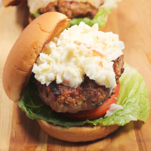 Closeup of grilled pork burger on bun with coleslaw.