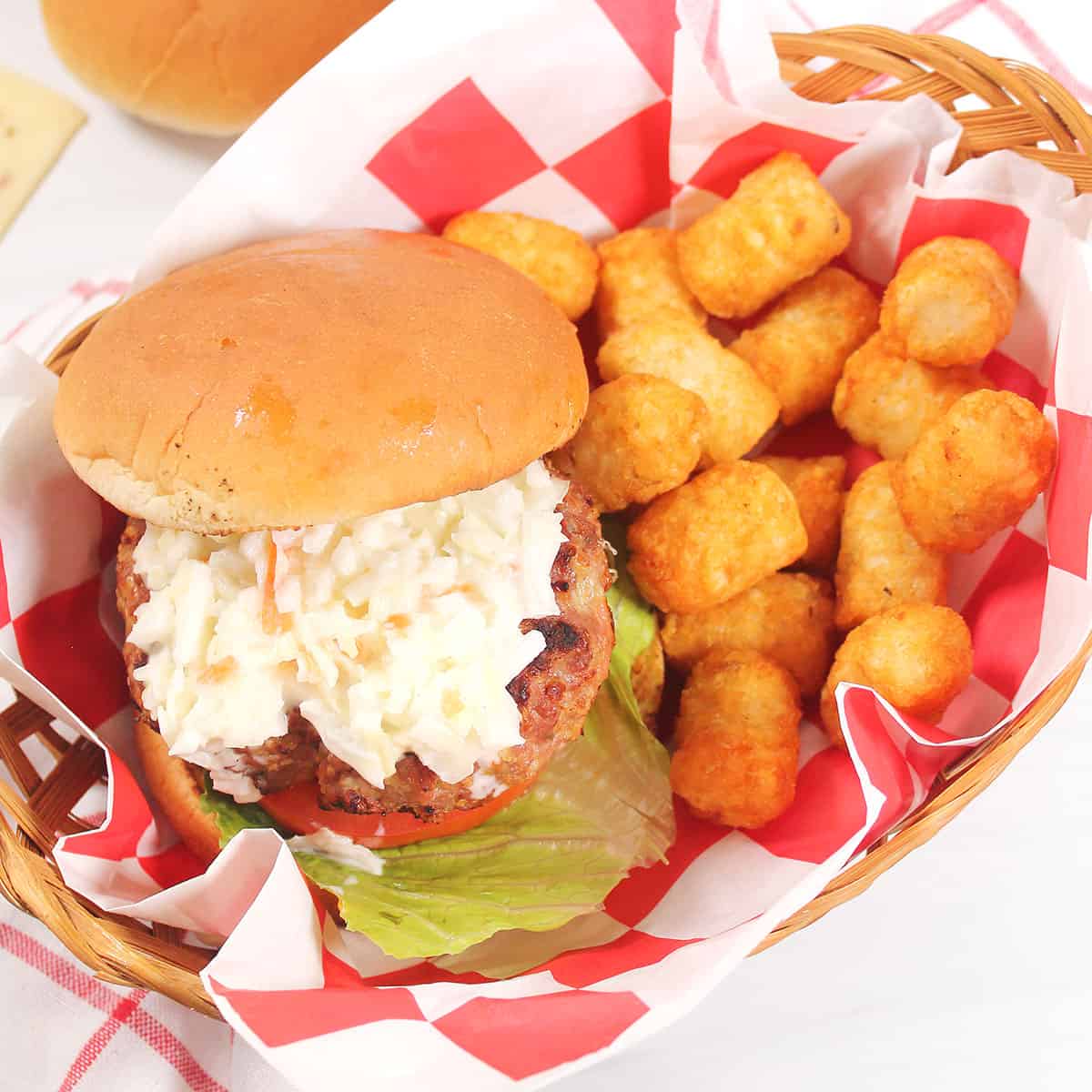 Pork burger on a bun with a side of tater tots.