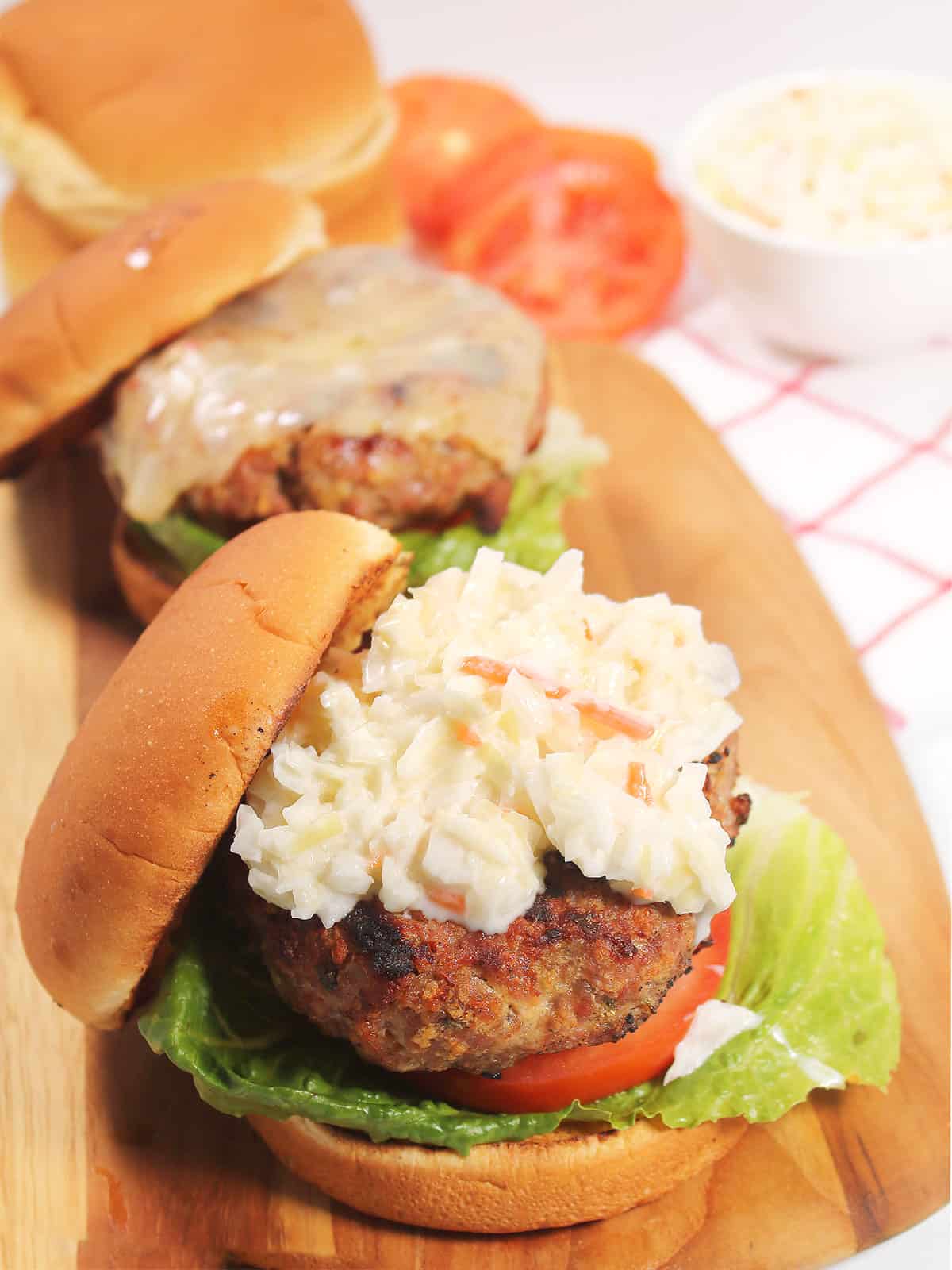 Pork burgers topped with coleslaw on buns.