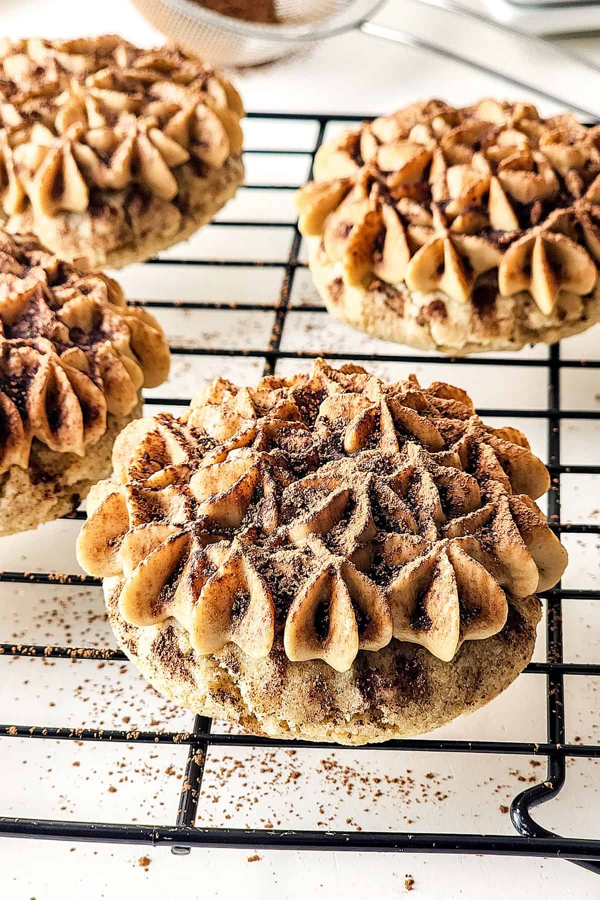 Tiramisu cookies with mascarpone frosting on wire cooling rack.