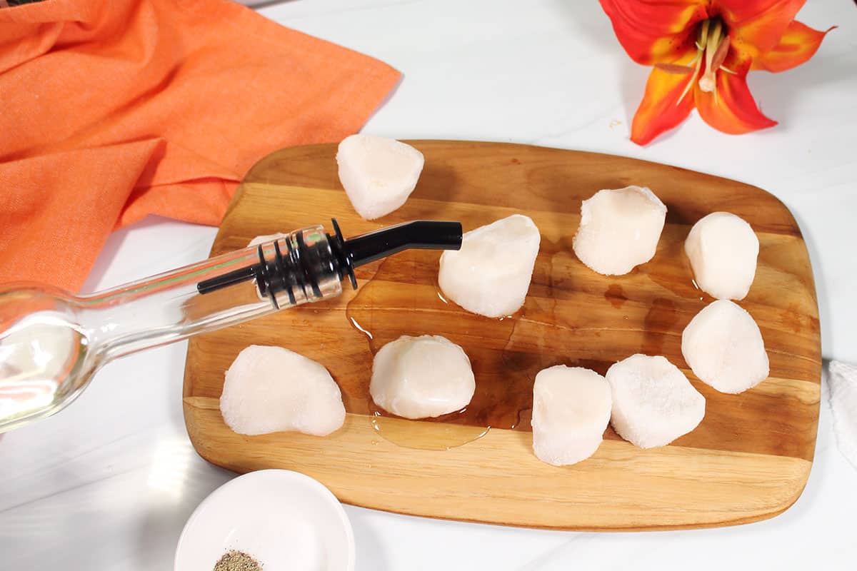 Drizzling the scallops with oil.