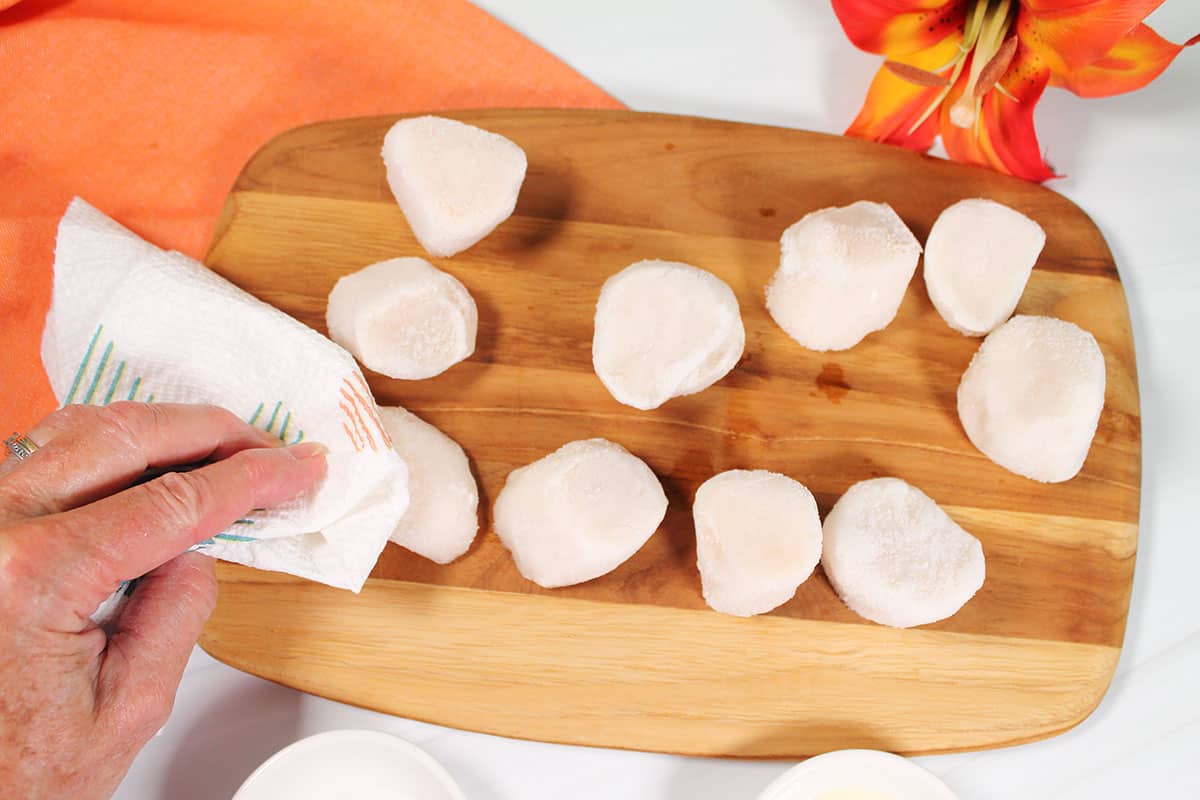 Patting the frozen scallops dry.
