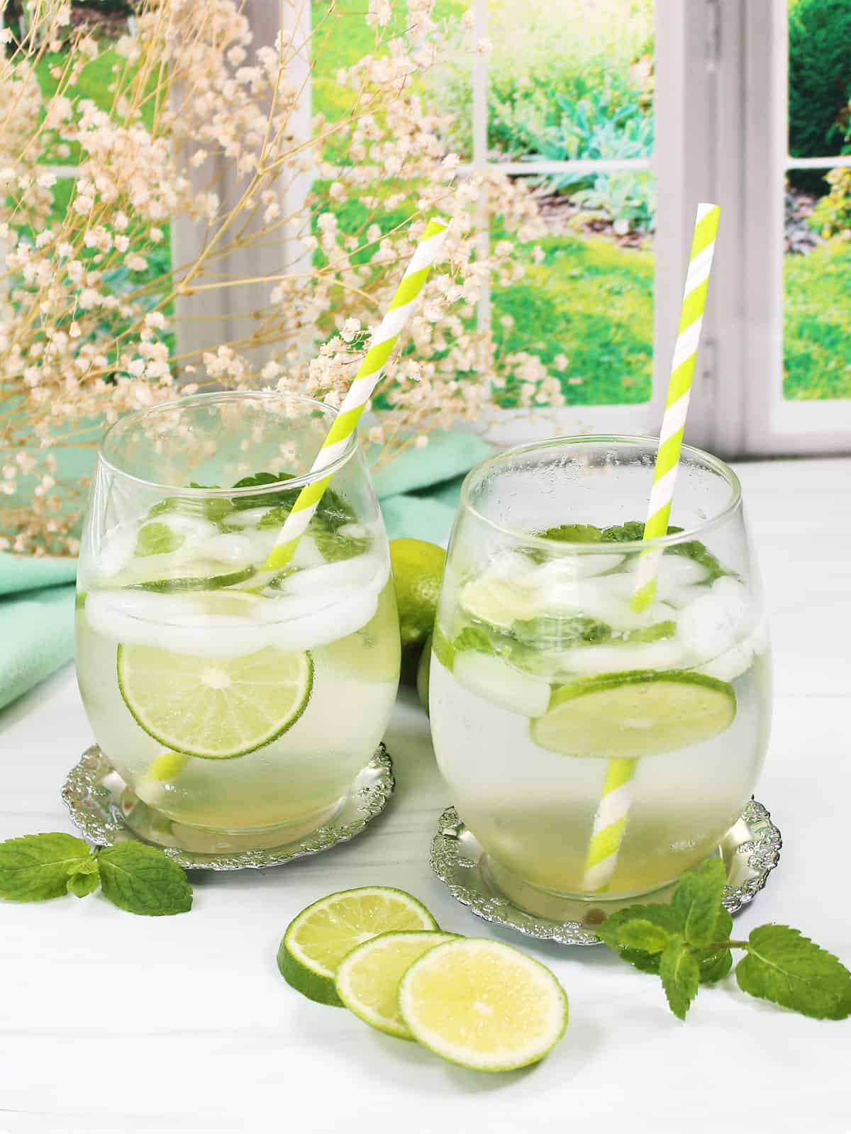 Two hugo spritz cocktails with mint and limes.