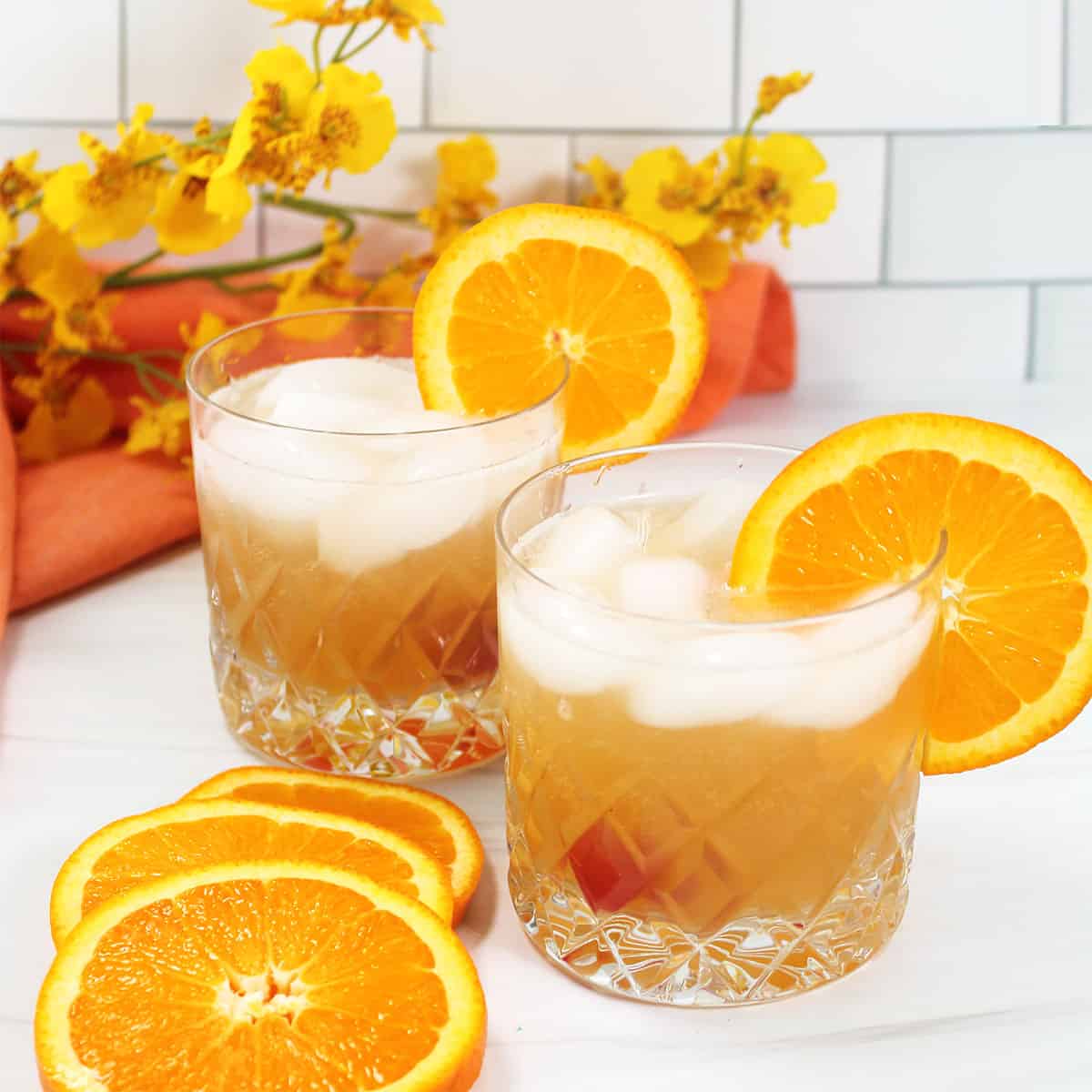 Two Amaretto Sour cocktails with orange garnish.