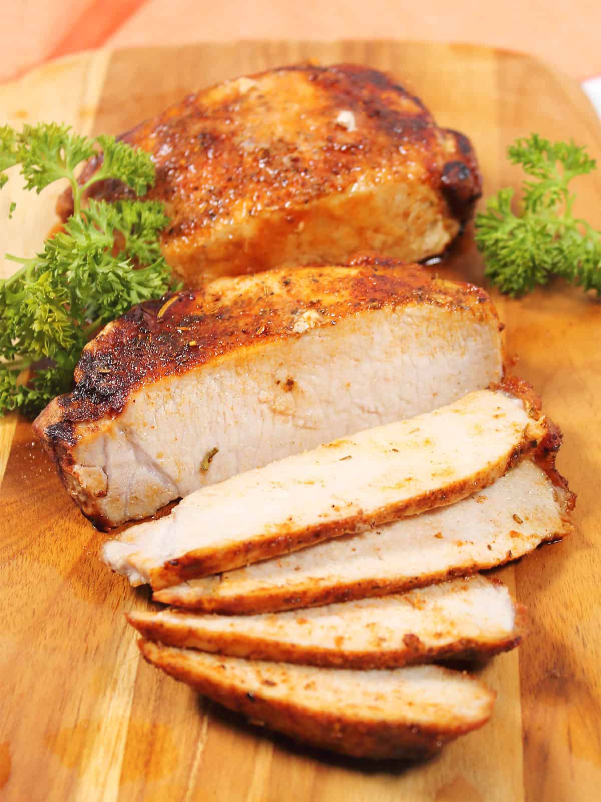 Sliced air fried frozen pork chops on cutting board.