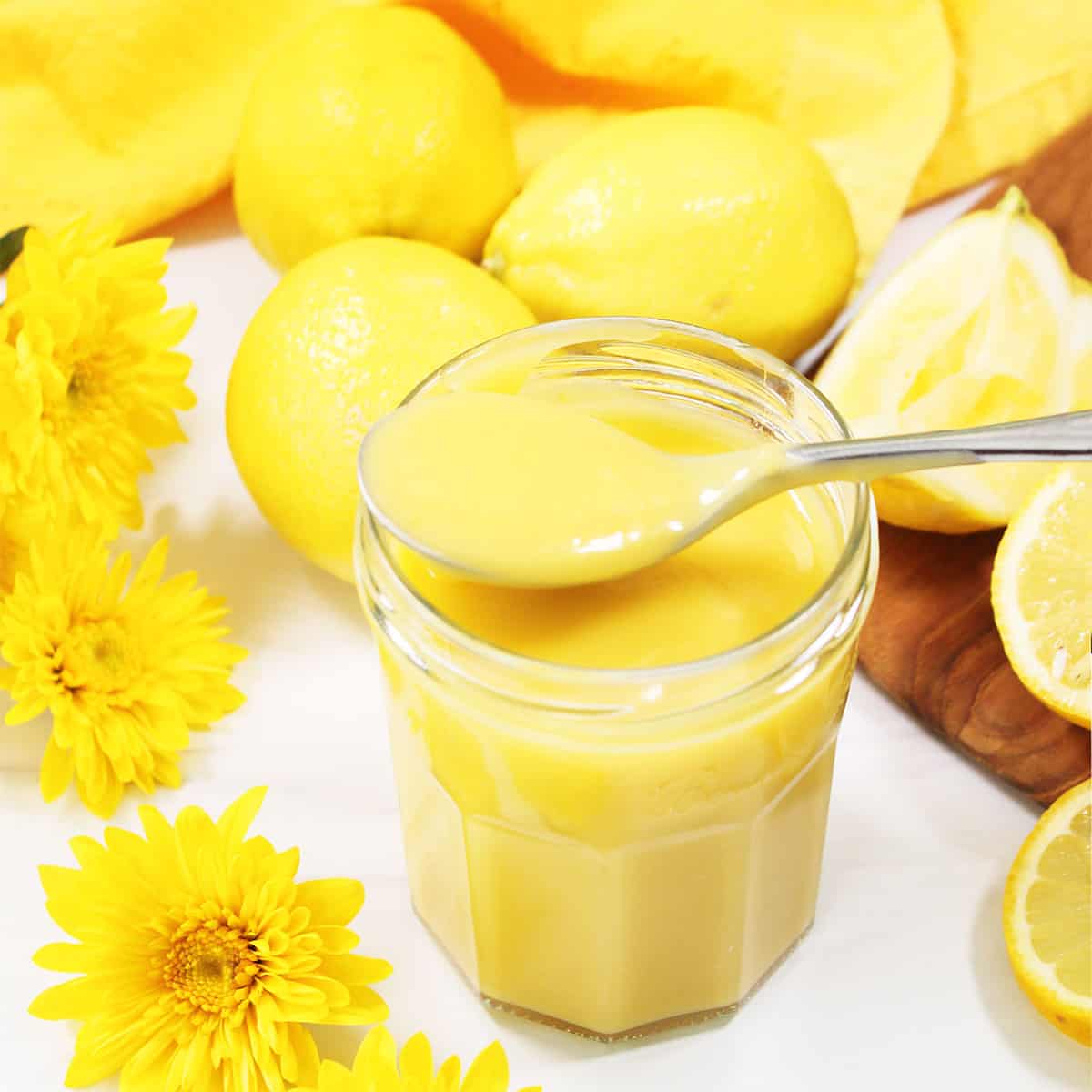 Homemade Lemon Curd in jar with spoonful on top.