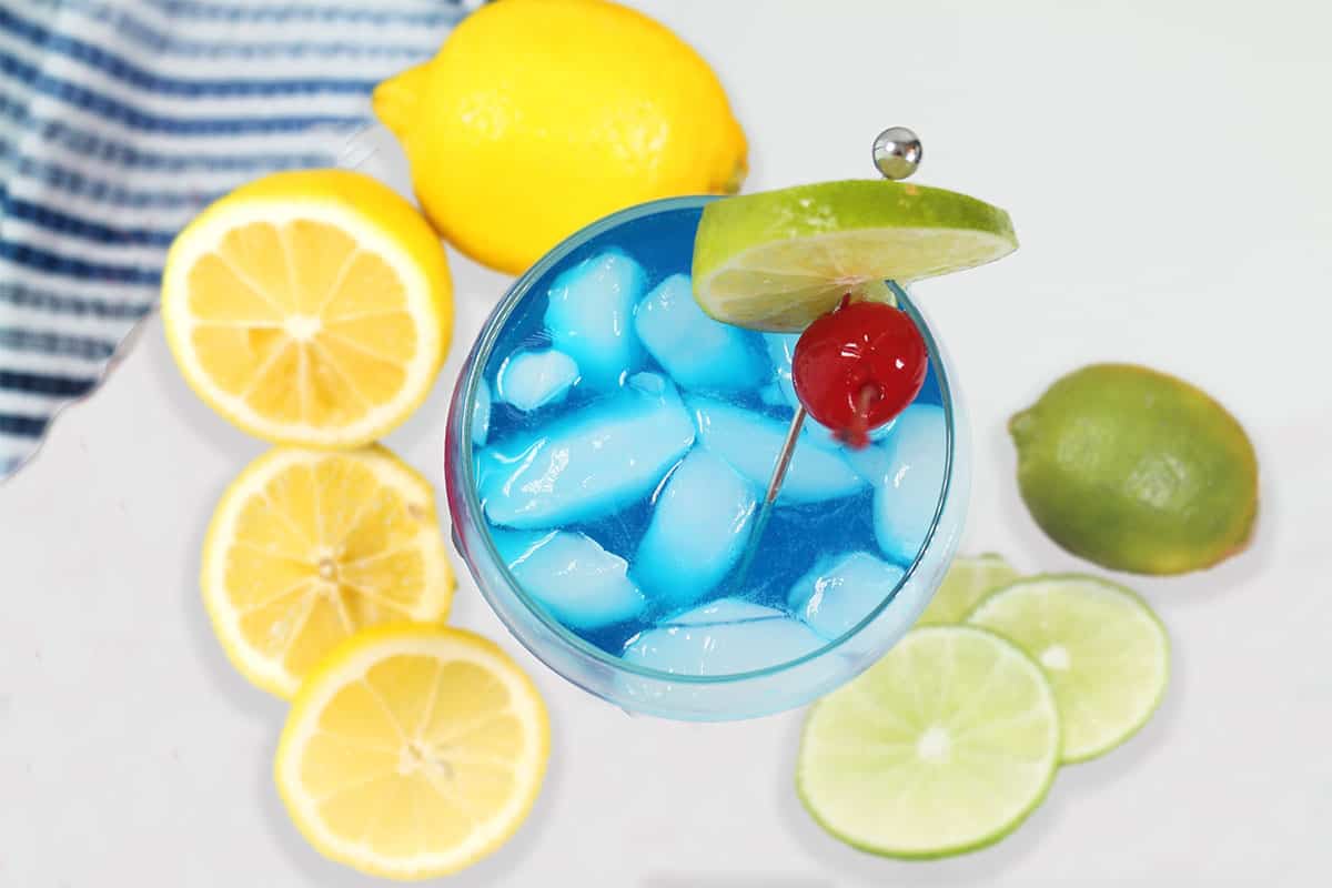 Overhead of smurf drink with lemons and limes.