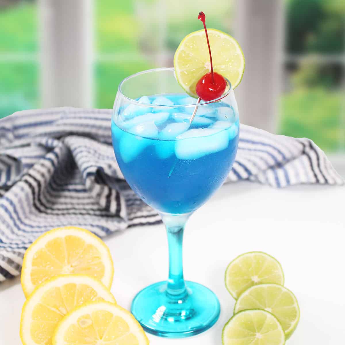 Papa Smurf Cocktail in wine glass with garnish.