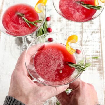 Holding a rosemary infused bourbon martini.