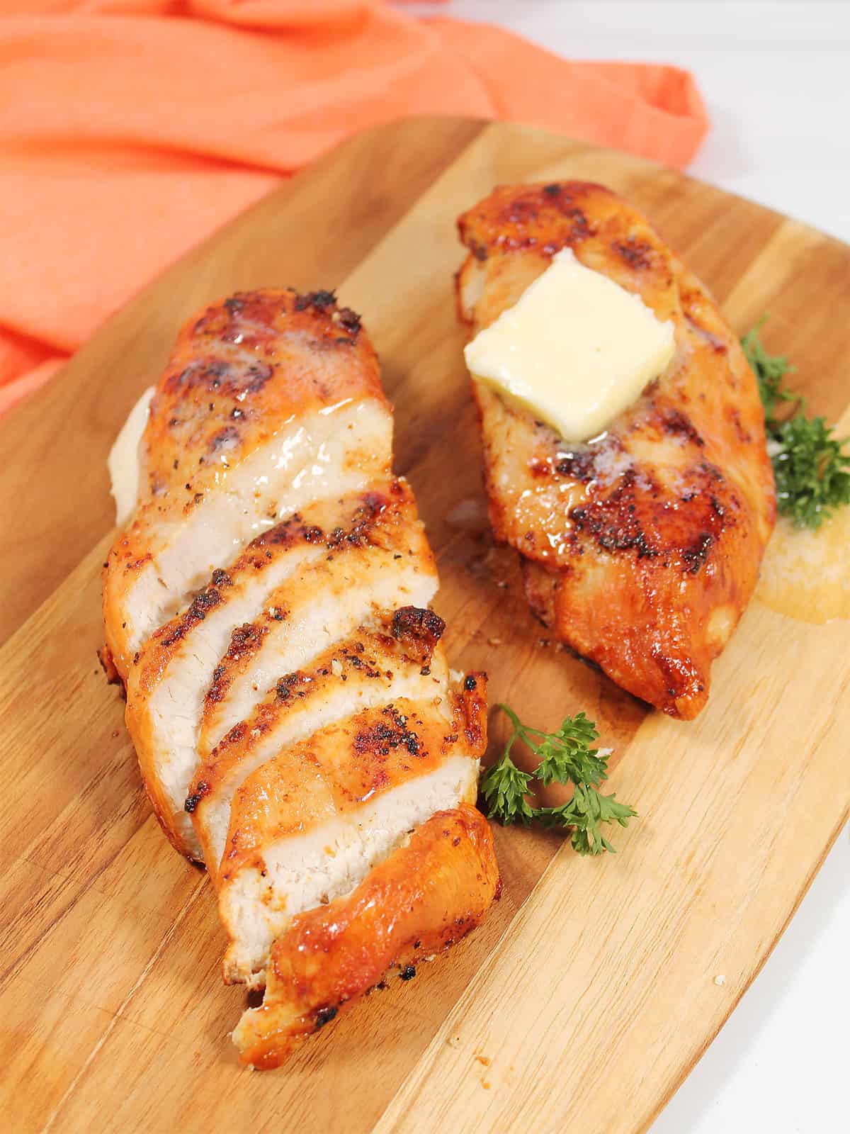 Golden brown and Juicy air fried chicken breasts on cutting board.