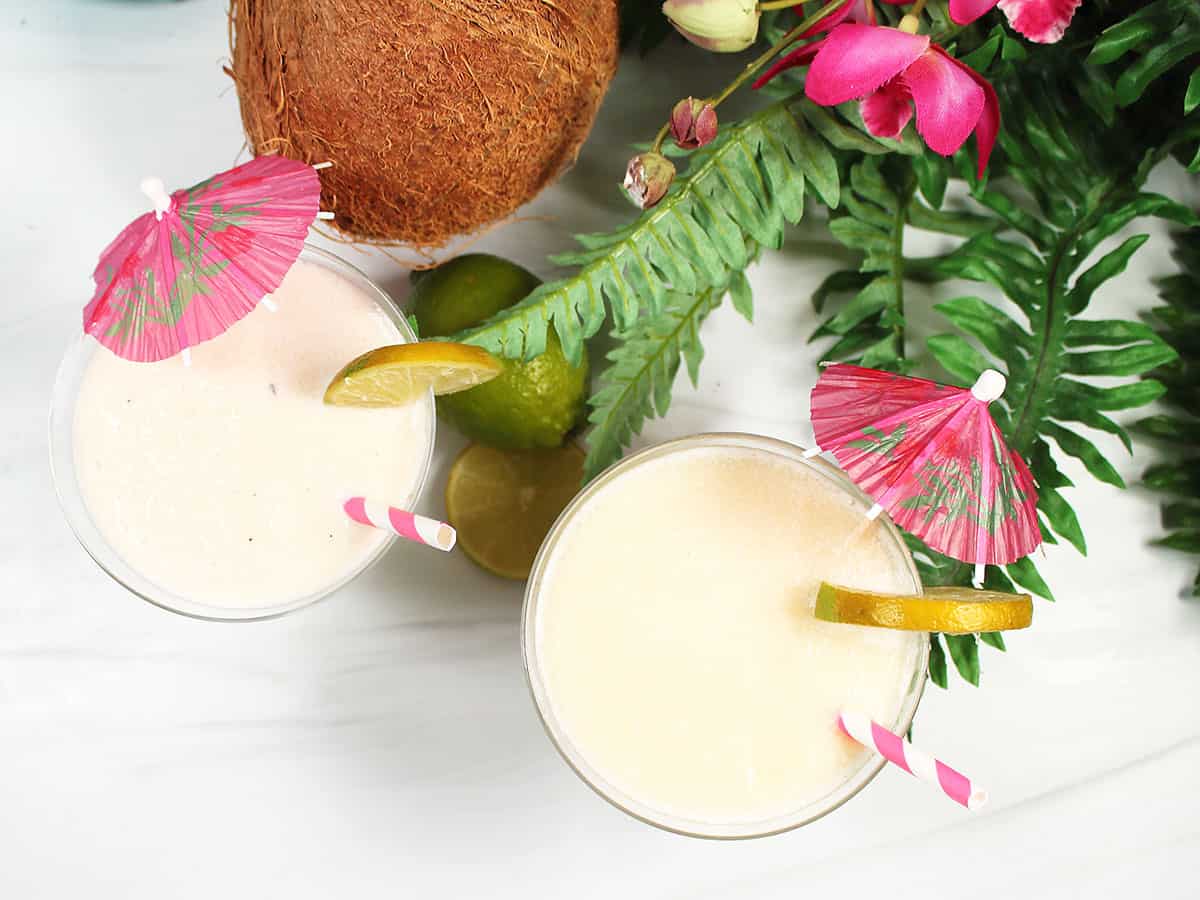 Overhead of two coconut daiquiris with umbrellas.