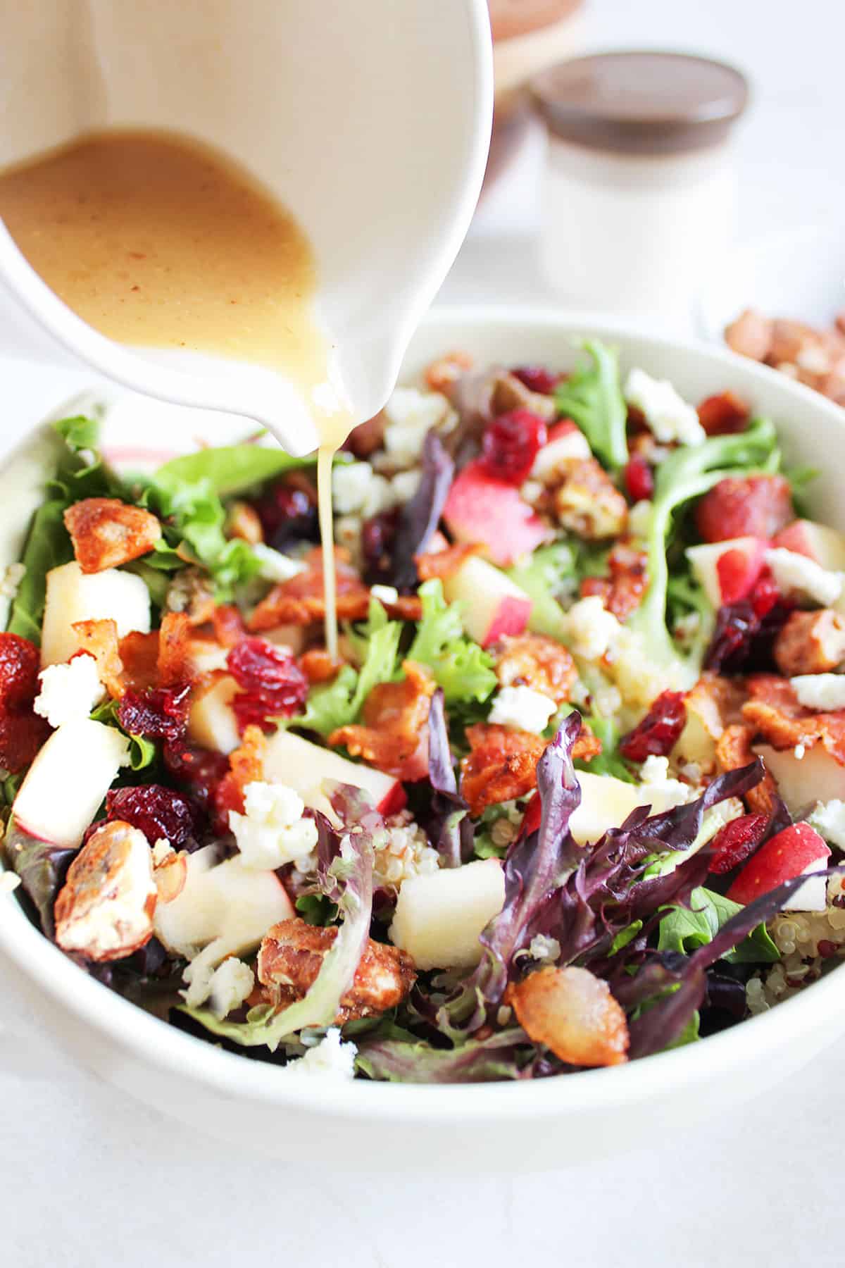Drizzling bacon vinaigrette over fall apple salad.