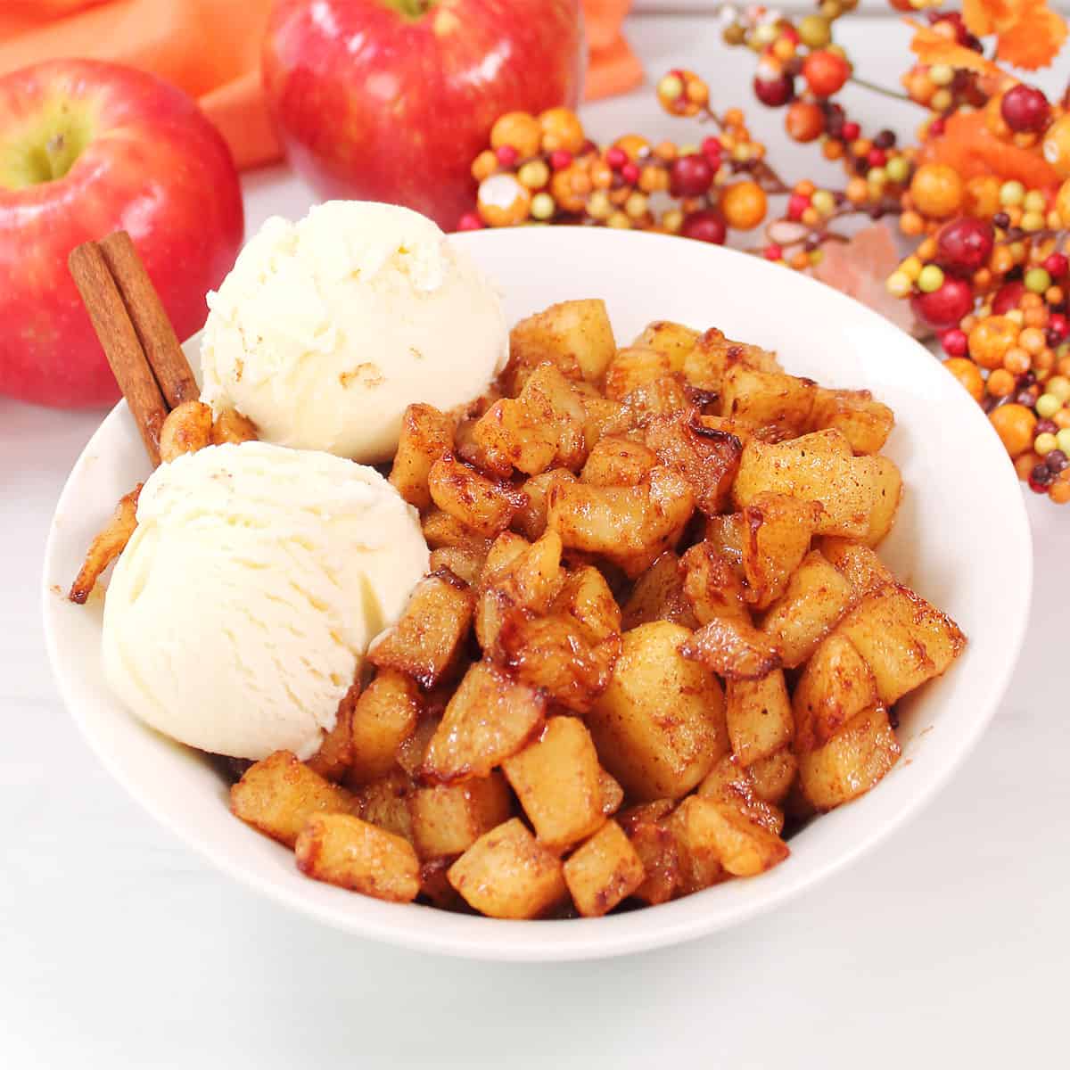Bowl of air fryer apples with ice cream and apples in back.