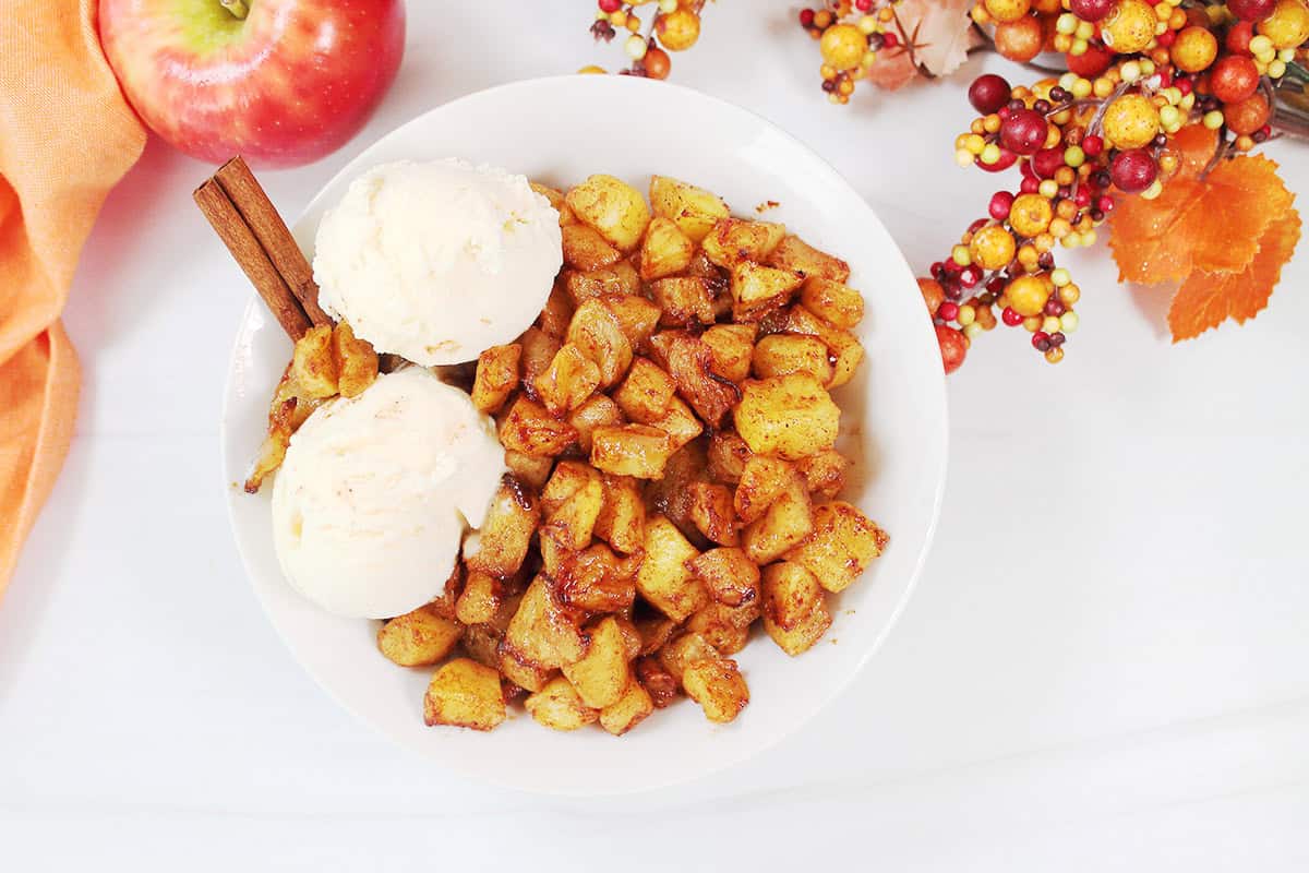 Overhead of air fryer cinnamon apples in bowl with ice cream.