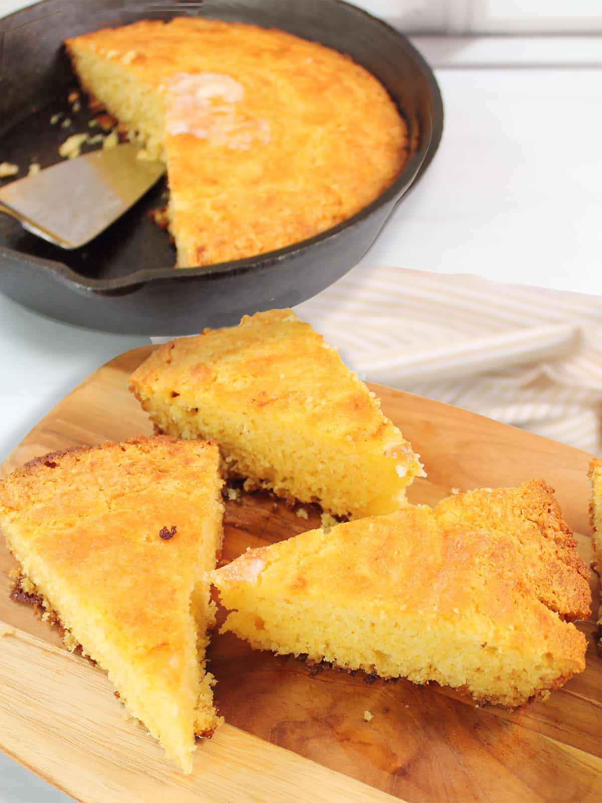 3 slices buttermilk skillet cornbread on wooden board.