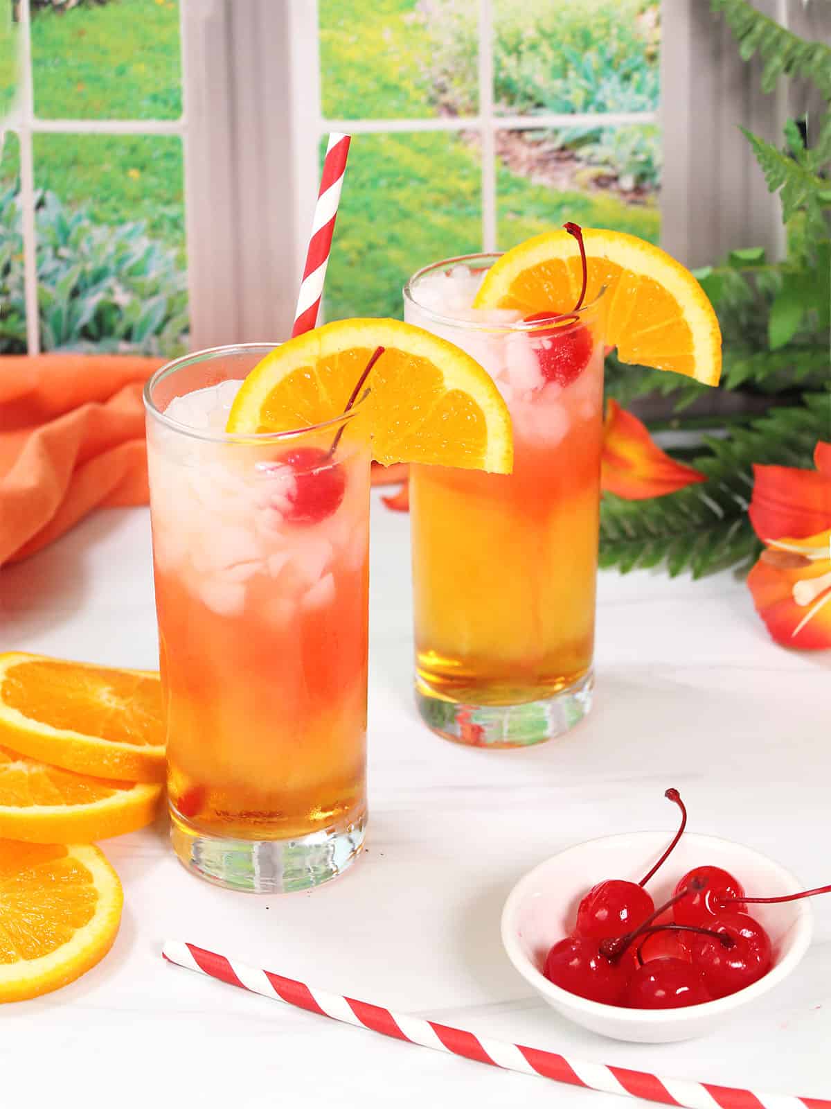 Two Italian Sunset Cocktails with orange slice, cherry and a straw.