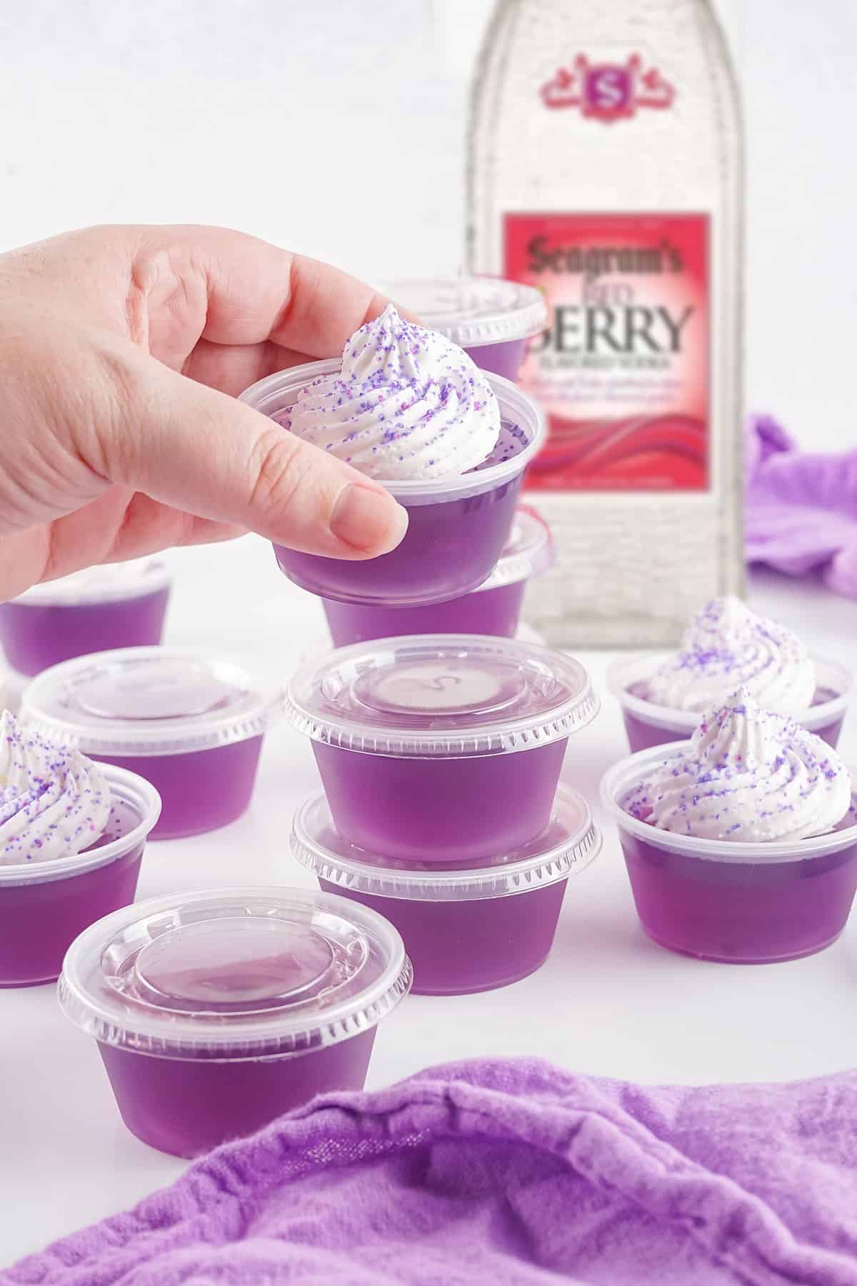Lifting Purple Hooter Jello Shot garnished with whipped cream.