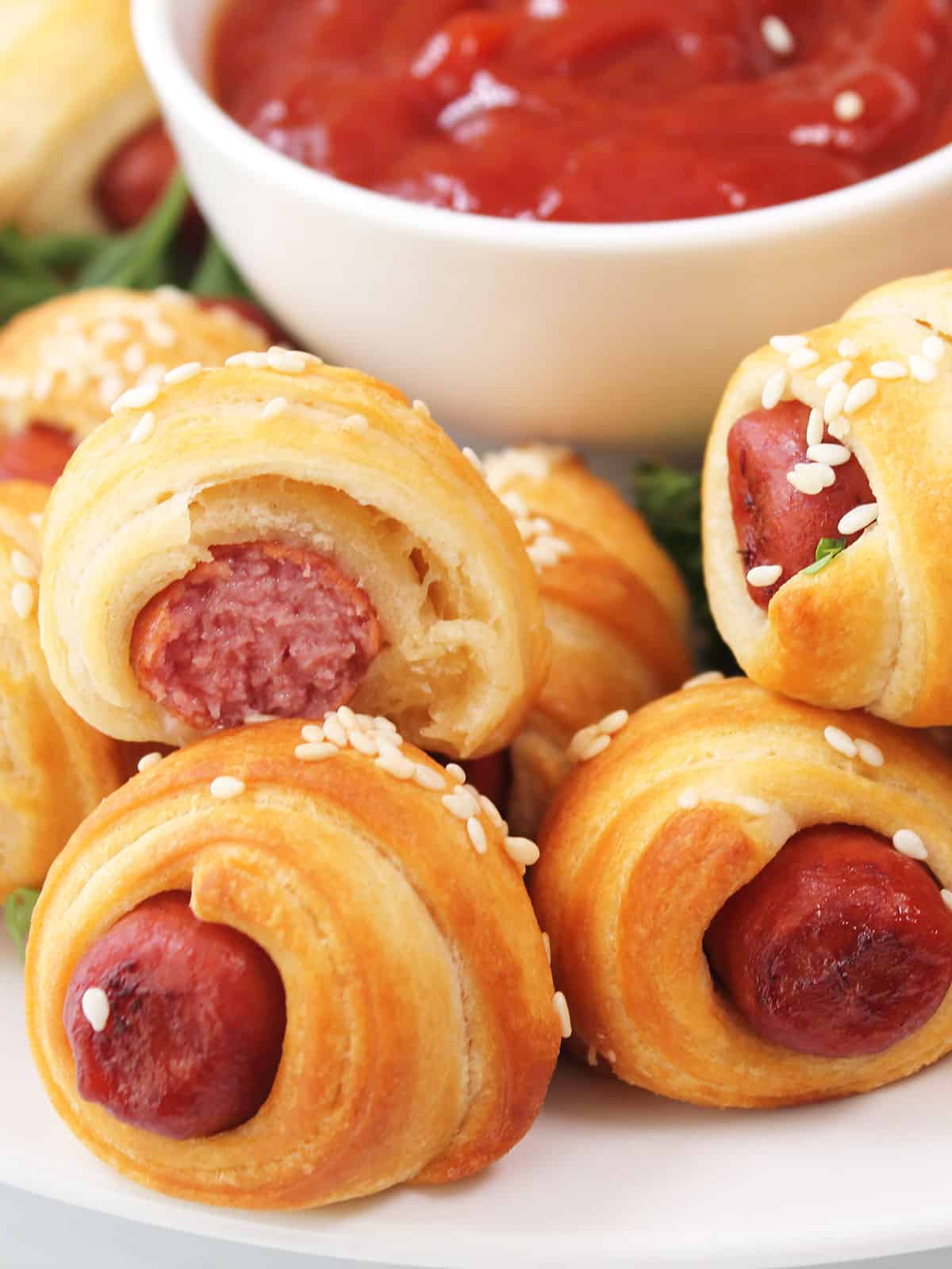 Closeup of air fried pigs in a blanket with bite out of one.