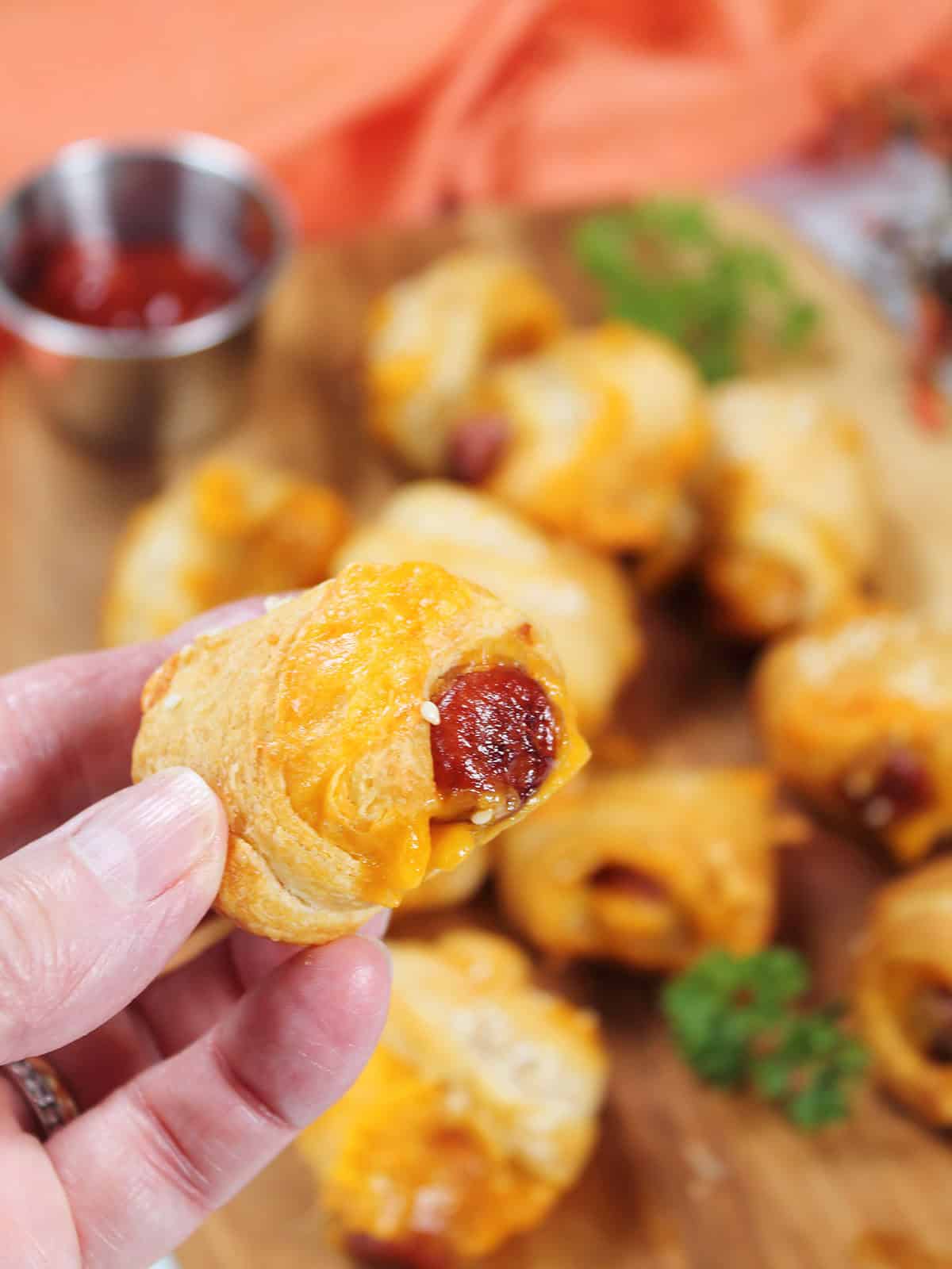 Holding pigs in blanket with cheese.