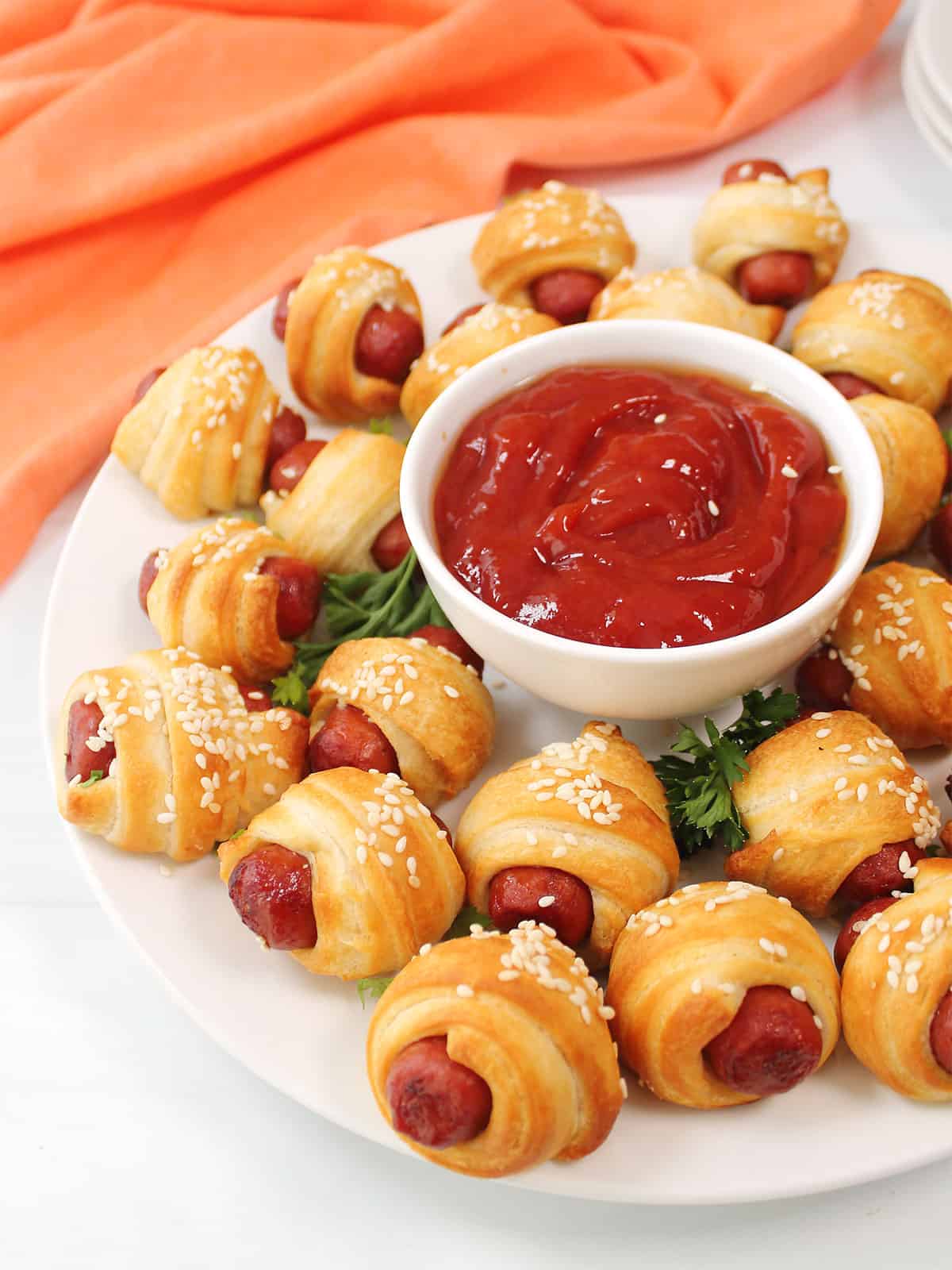 Plated air fryer pigs in a blanket with parsley garnish and ketchup.