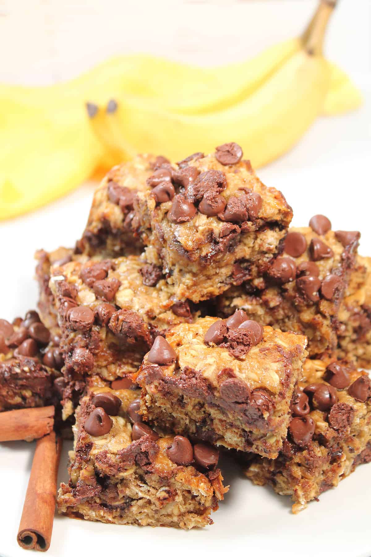 Pile of oatmeal chocolate chip bars with cinnamon sticks.
