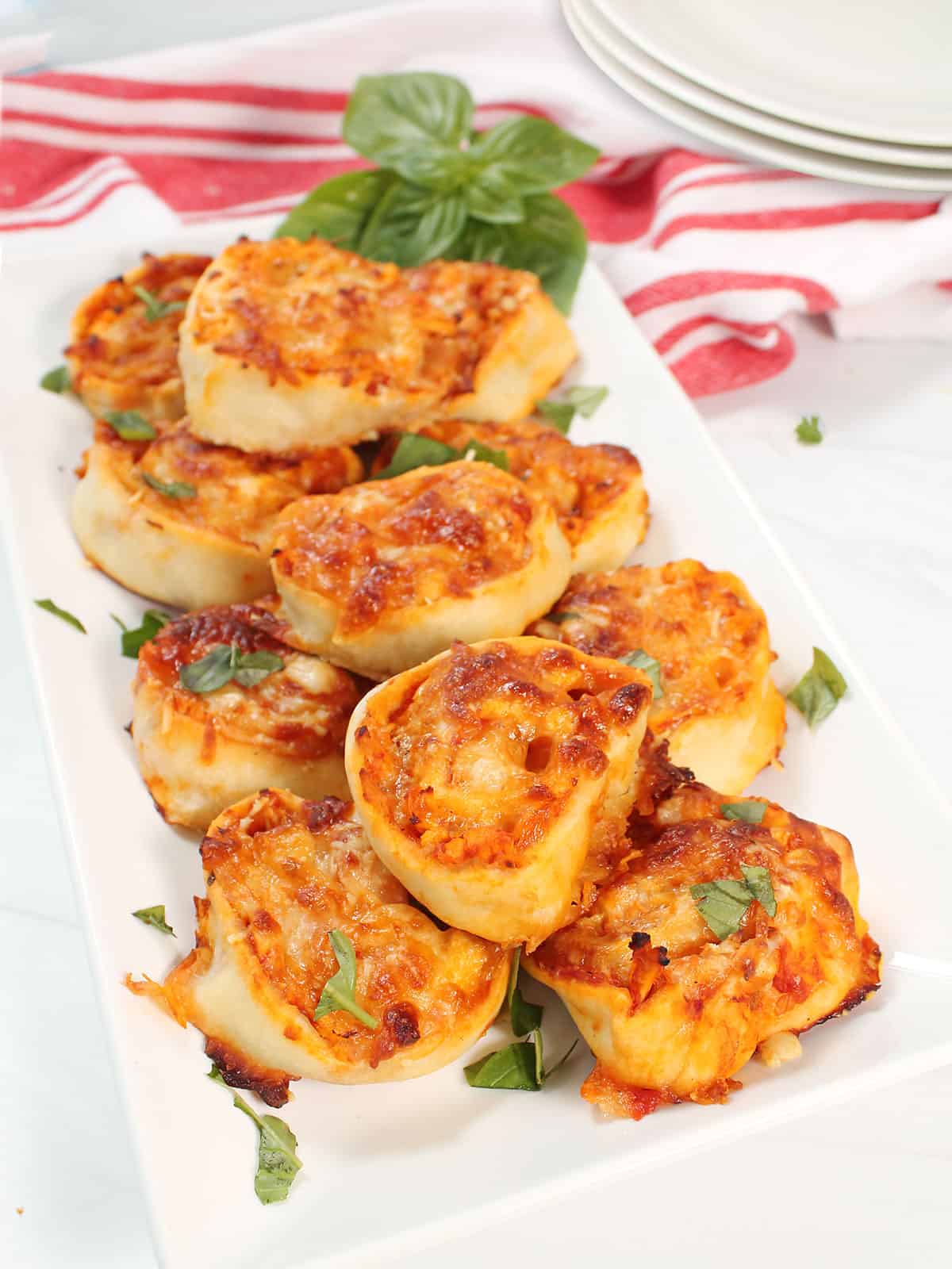 Chicken Parmesan Pinwheels on platter sprinkled with basil.